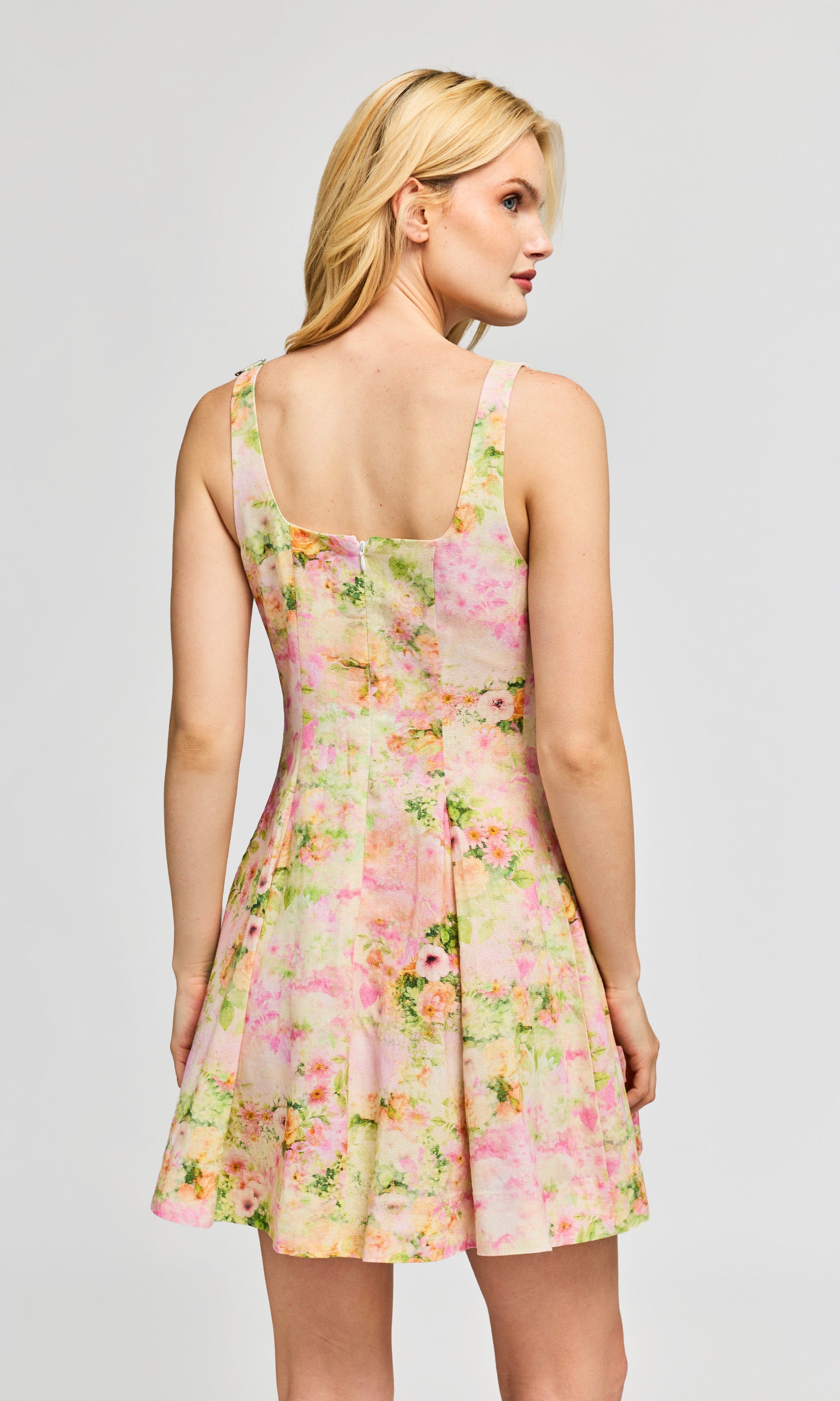 Back view of woman wearing a floral dress on a plain background