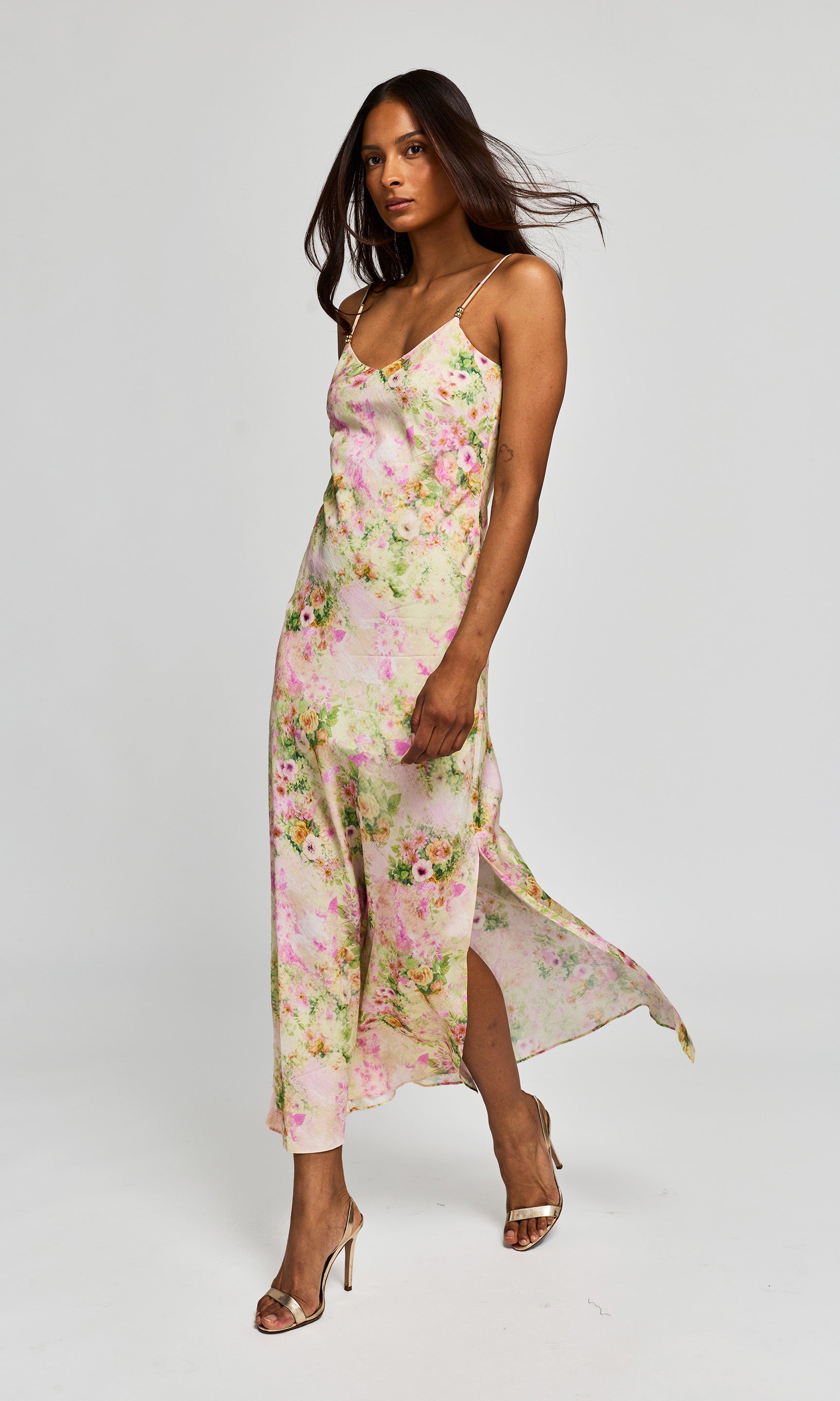Side view of woman wearing a floral slip dress on a white background