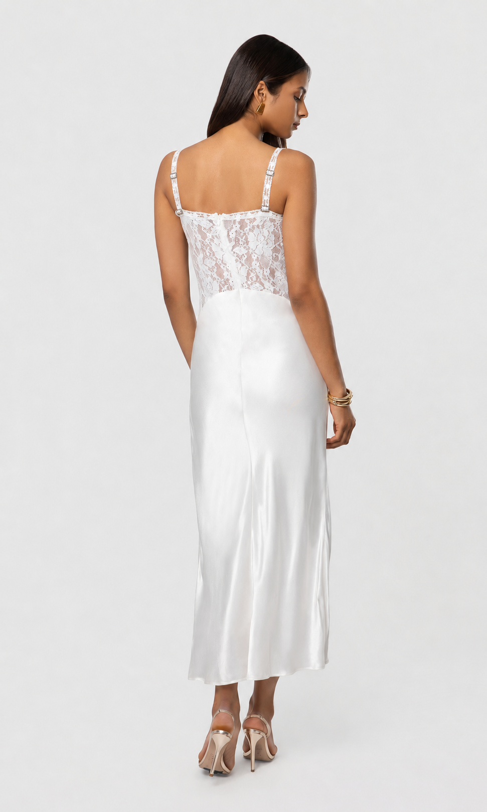 Back view of woman wearing a white dress with lace detailing on a white background