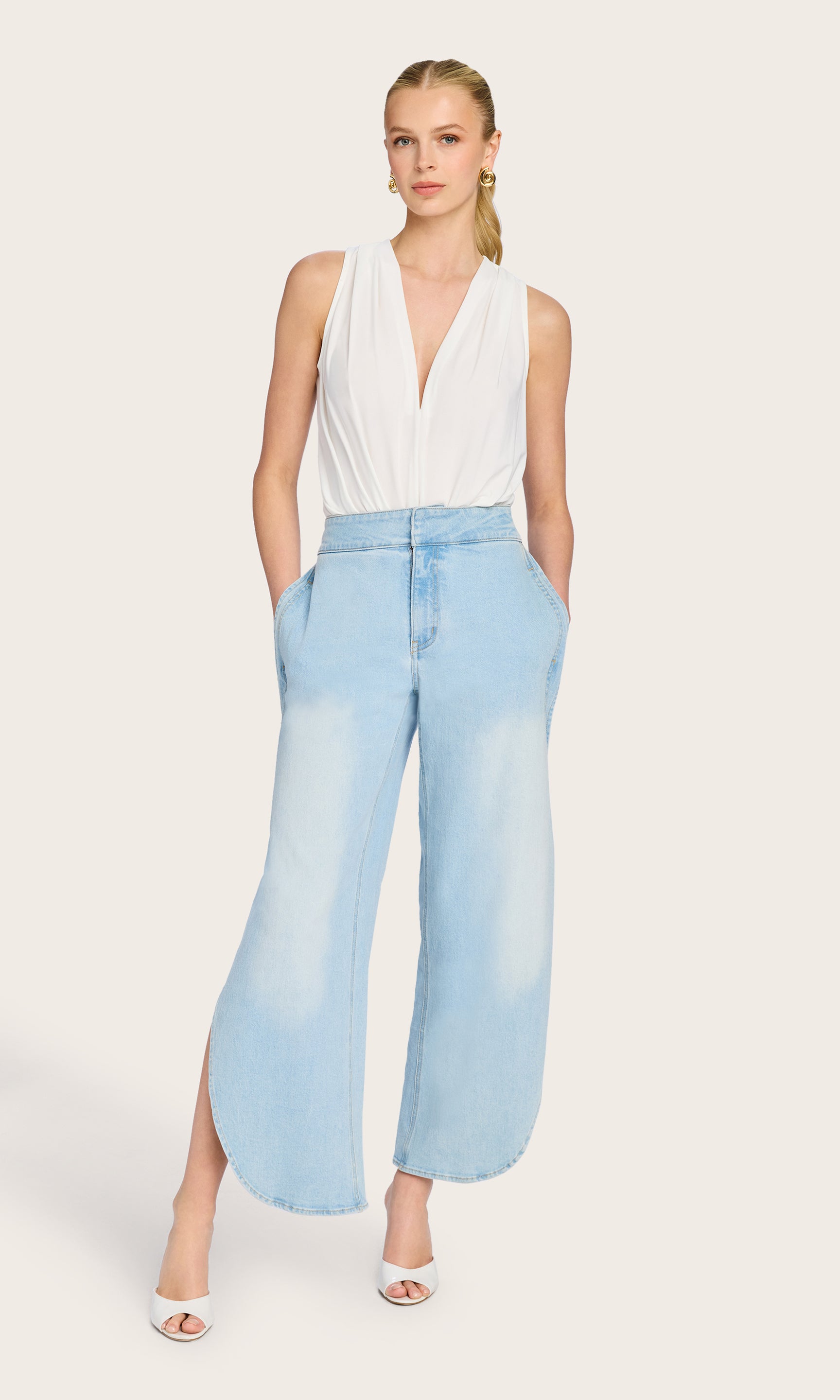 The model stands in a front full-body view wearing the Ansel Bodysuit, paired with denim for a casual yet elevated look.