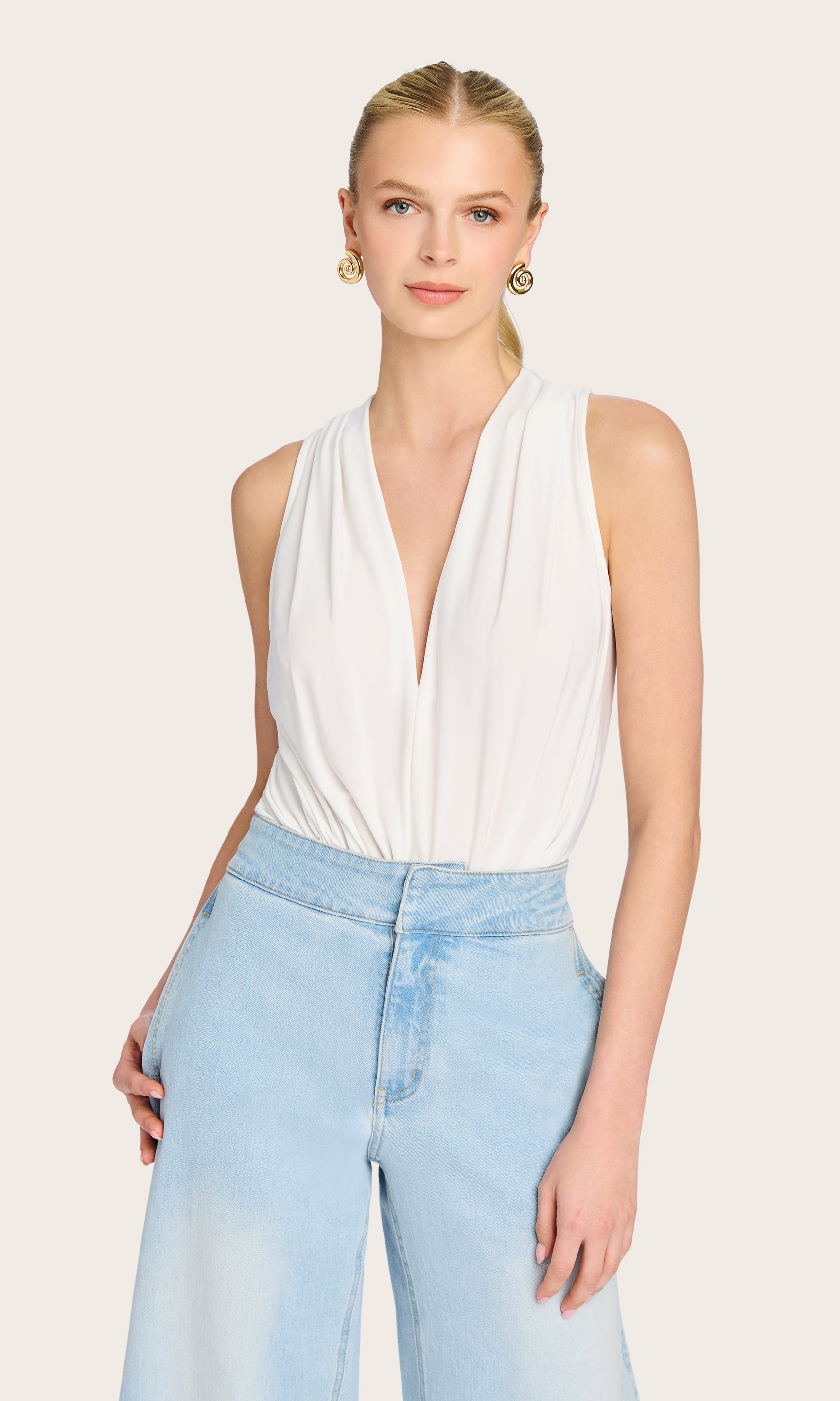 The model wears the Ansel Bodysuit in a front view, showcasing the deep V-neck design and effortless silhouette.