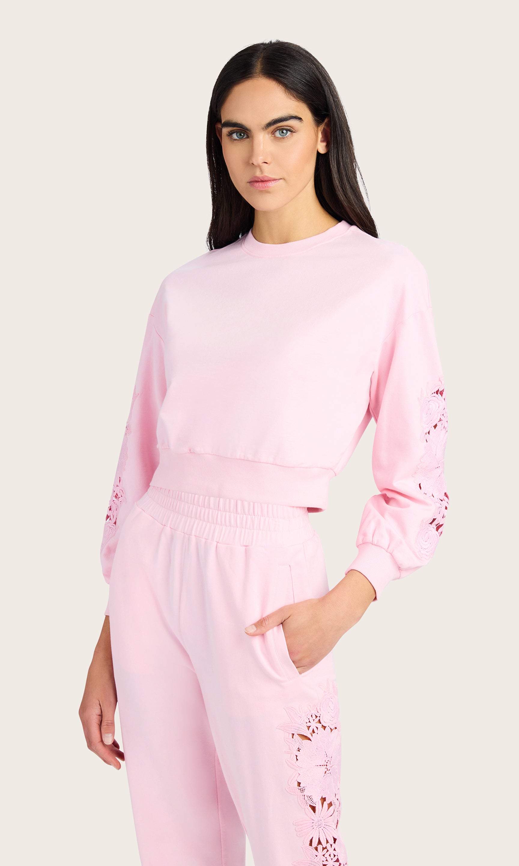 front view of model wearing the Arabella pink sweatshirt with lace detail on the sleeves, paired with matching pink joggers