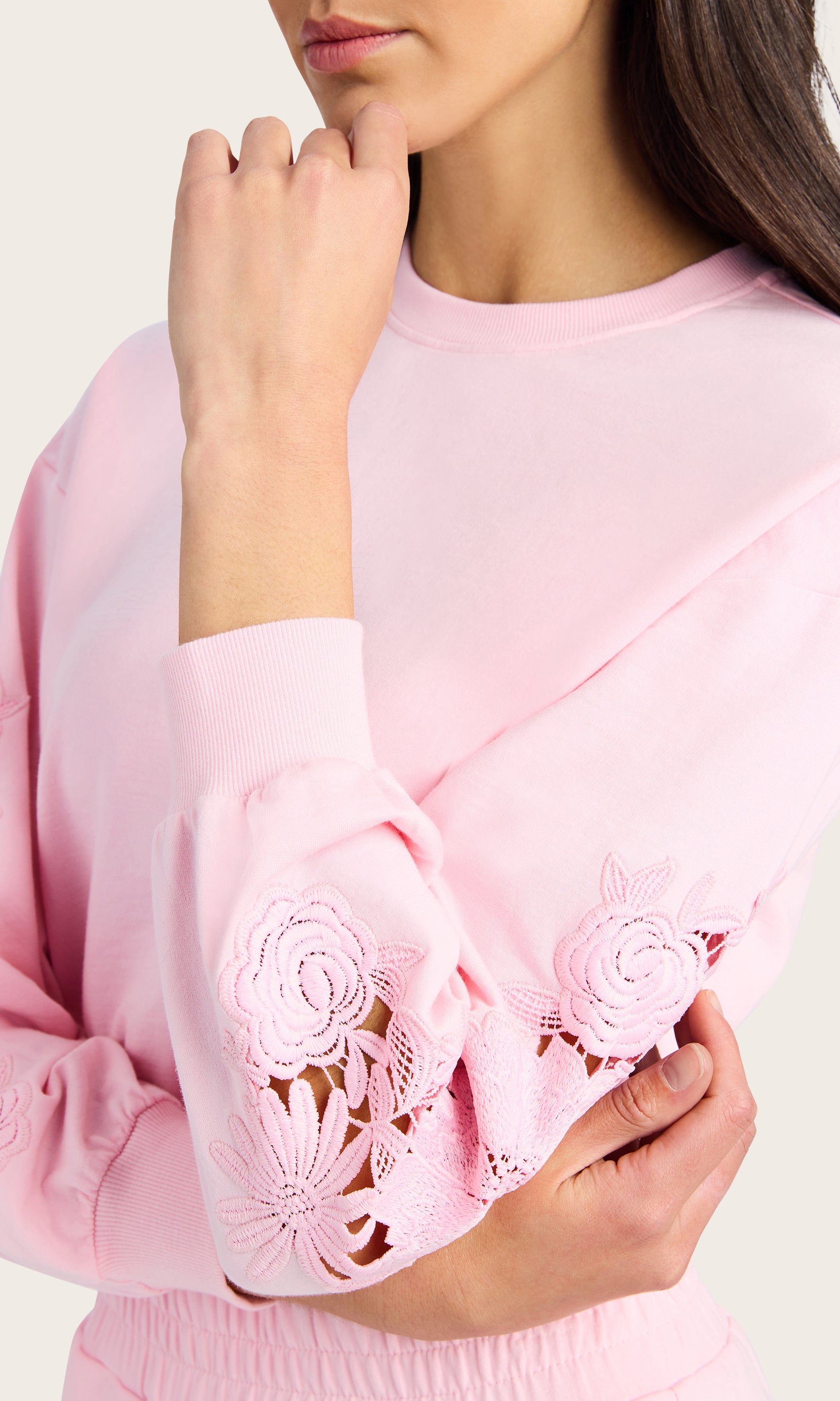 detailed view of model wearing the Arabella pink sweatshirt with lace detail on the sleeves, paired with matching pink joggers