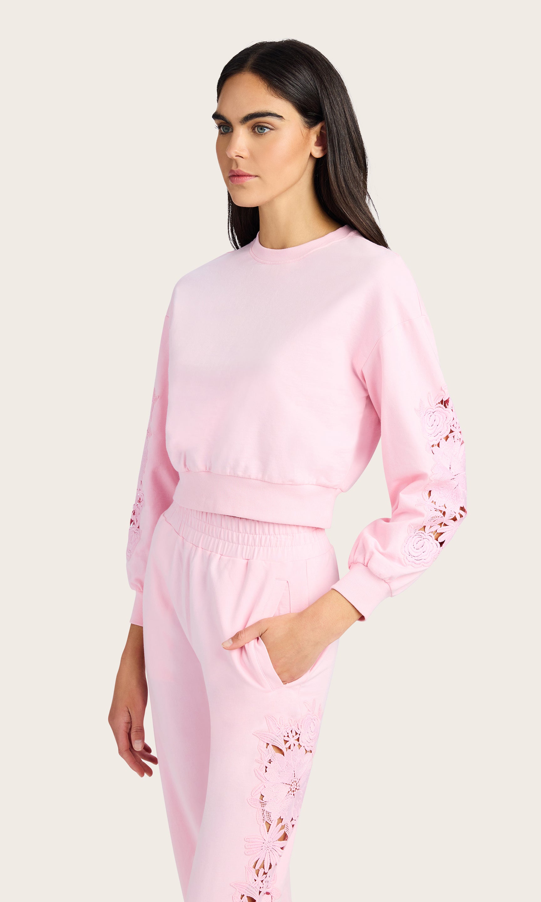 3/4 front view of model wearing the Arabella pink sweatshirt with lace detail on the sleeves, paired with matching pink joggers