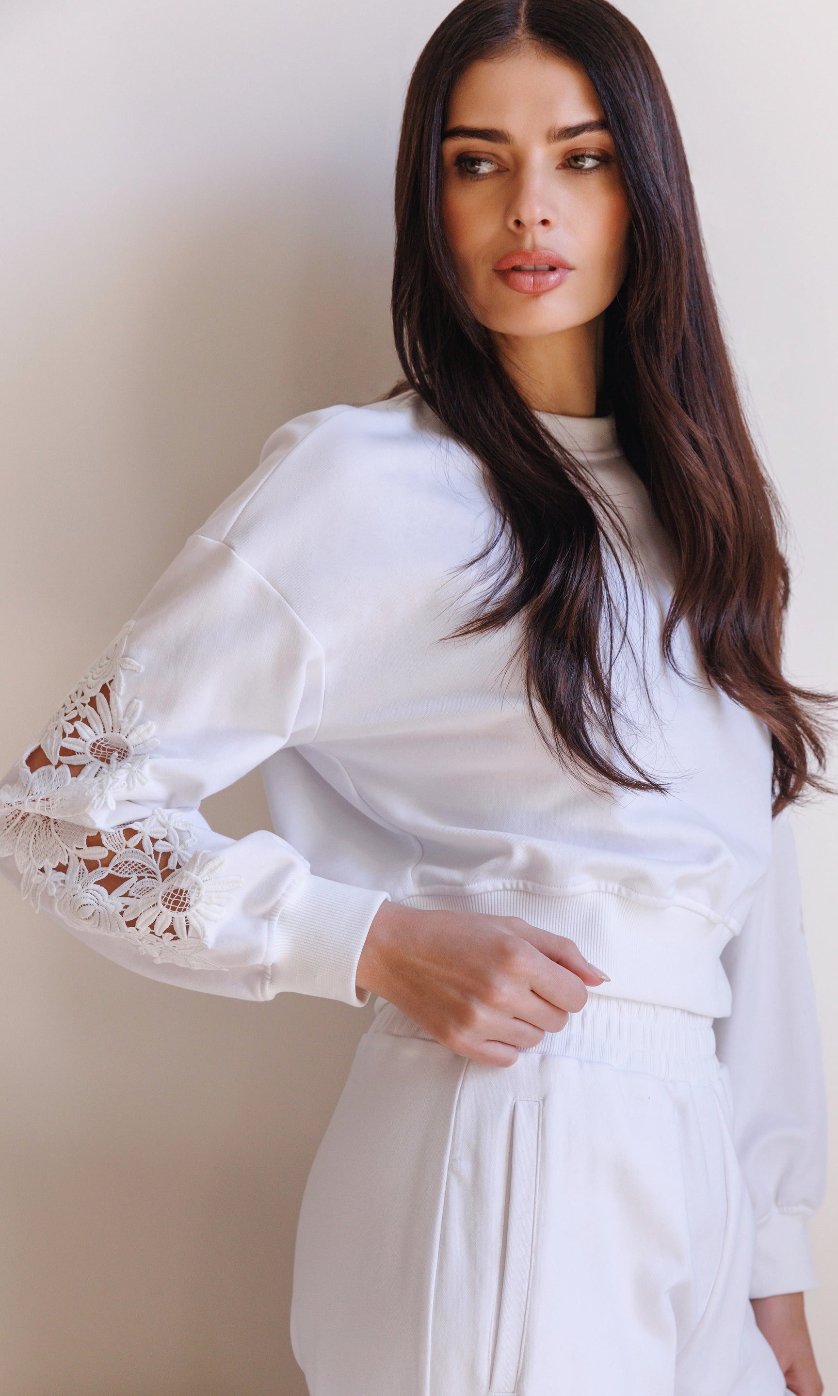 The model wears the Arabella Lace Combo Sweatshirt in white in a three-quarter front view, highlighting the lace sleeve detailing and relaxed sweatshirt fit styled as a matching set.