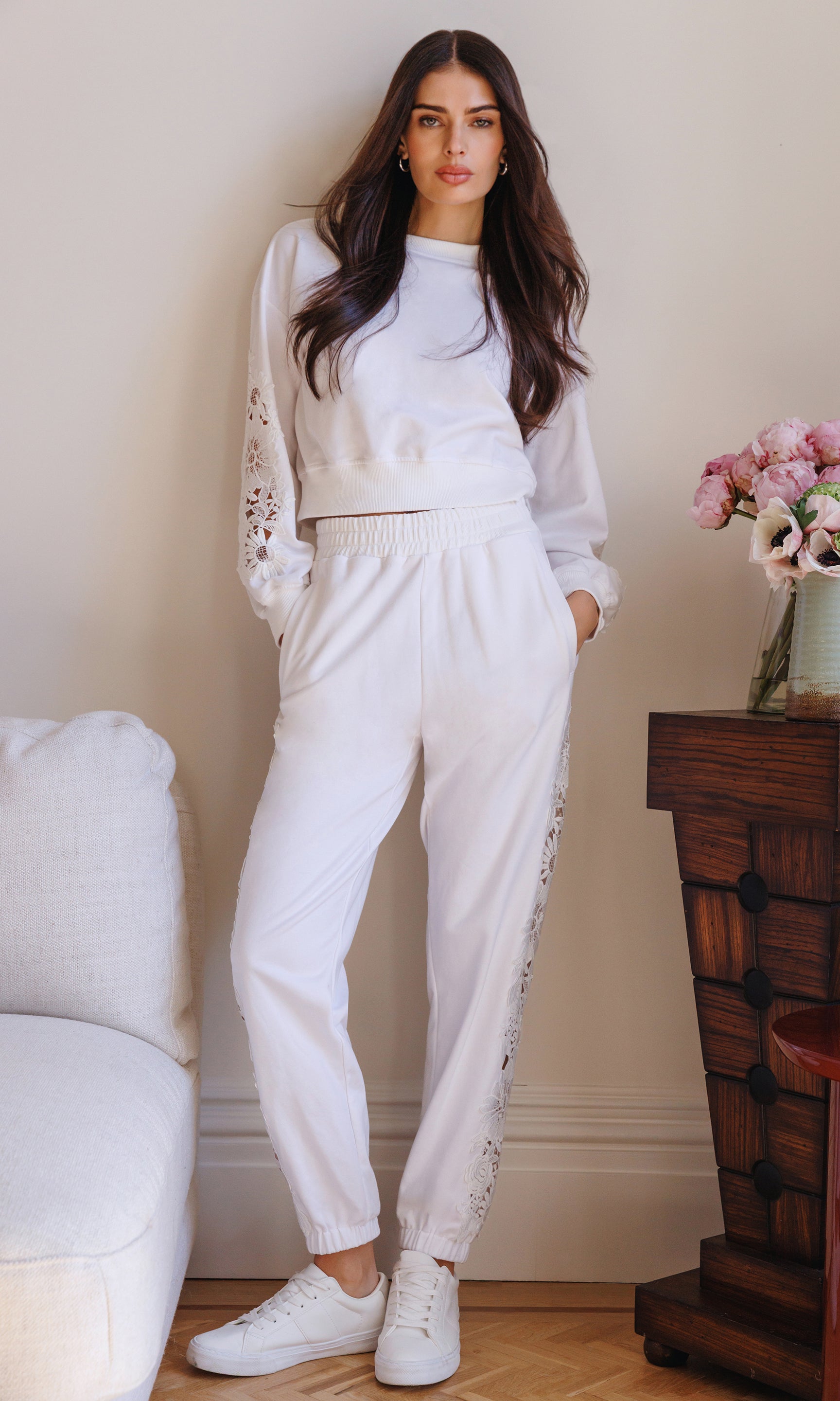 The model appears in a full body front view wearing the Arabella Lace Combo Sweatshirt in white with matching joggers, showing the cozy silhouette with lace accents.