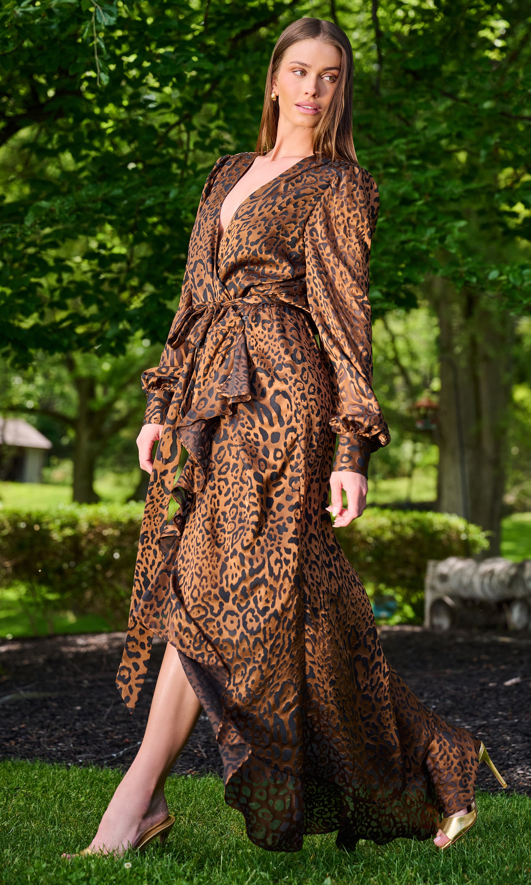 A woman wearing a brown and black leopard-print maxi dress with a tie waist and long sleeves.