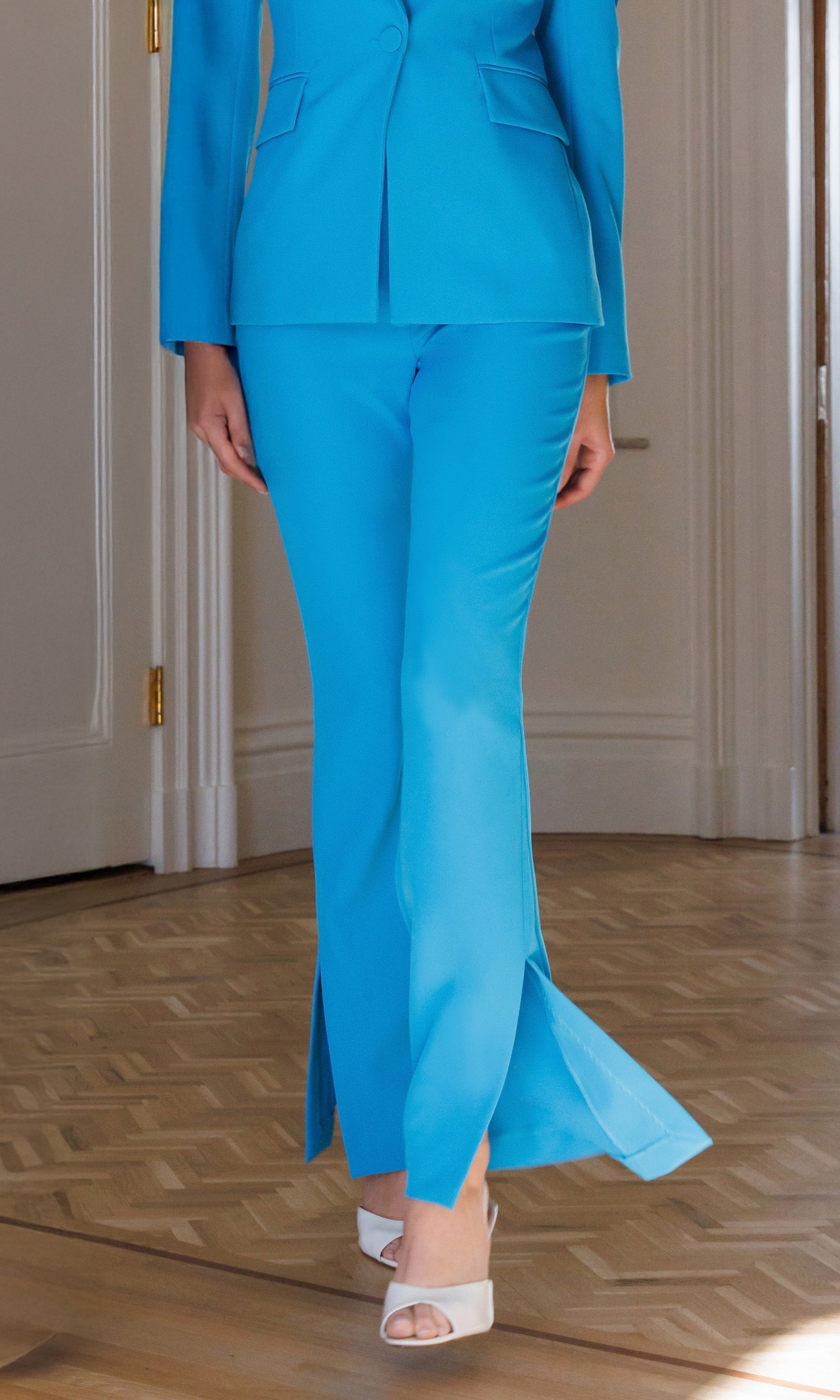 Person wearing a bright blue suit standing on a wooden floor.