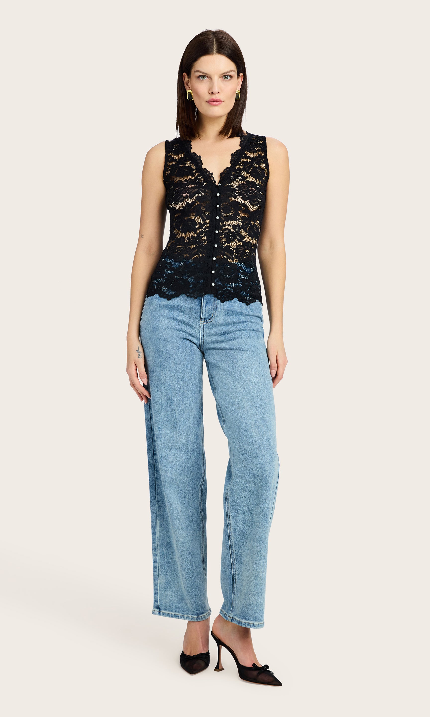 full body image of model wearing the Brinley lace tank in black with petite pearl buttons down the front, paired with blue denim jeans and black mesh kitten heels