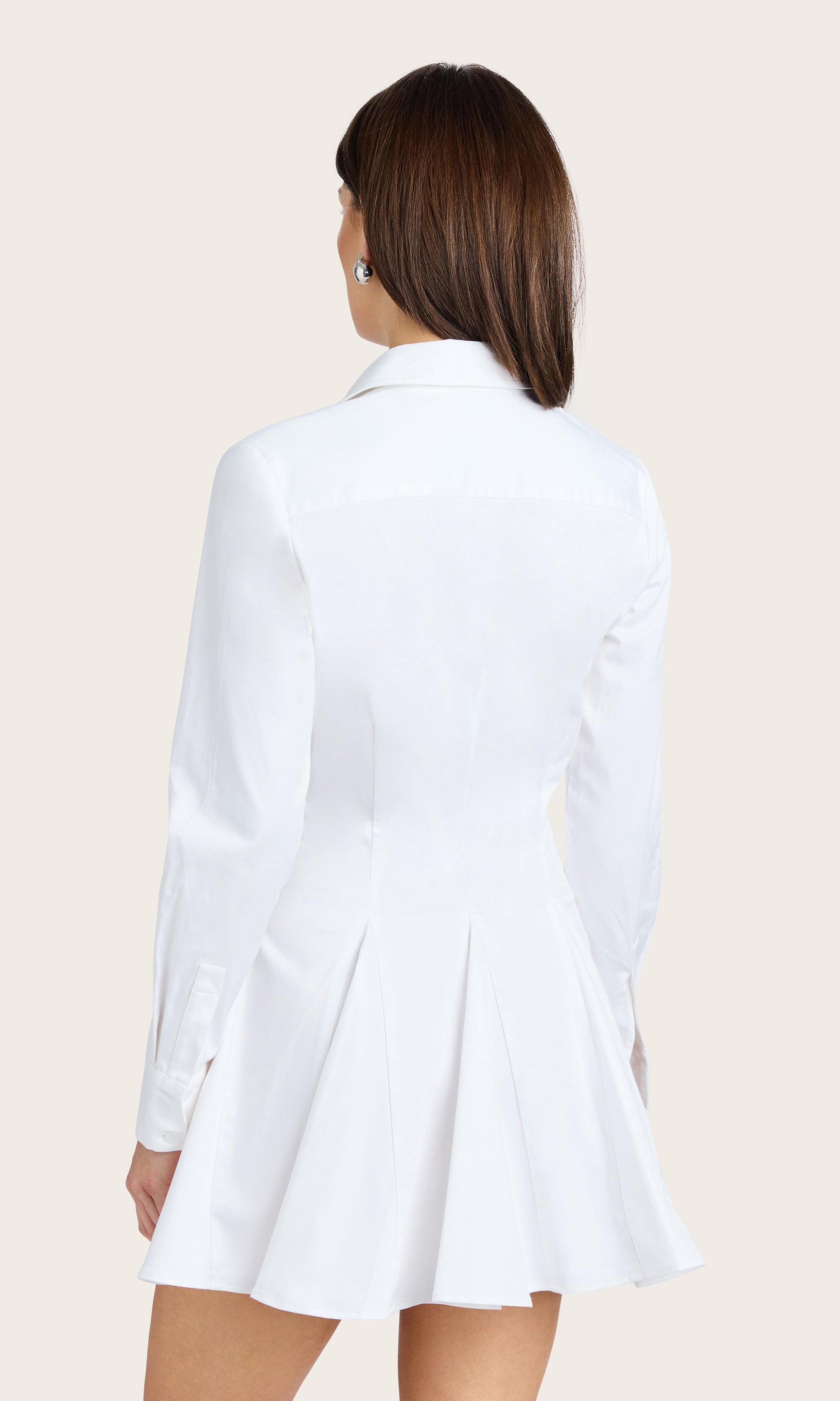 Rear view of the model wearing the Clemente Cotton Sateen Dress, showcasing the back silhouette and shirt-tail hem.
