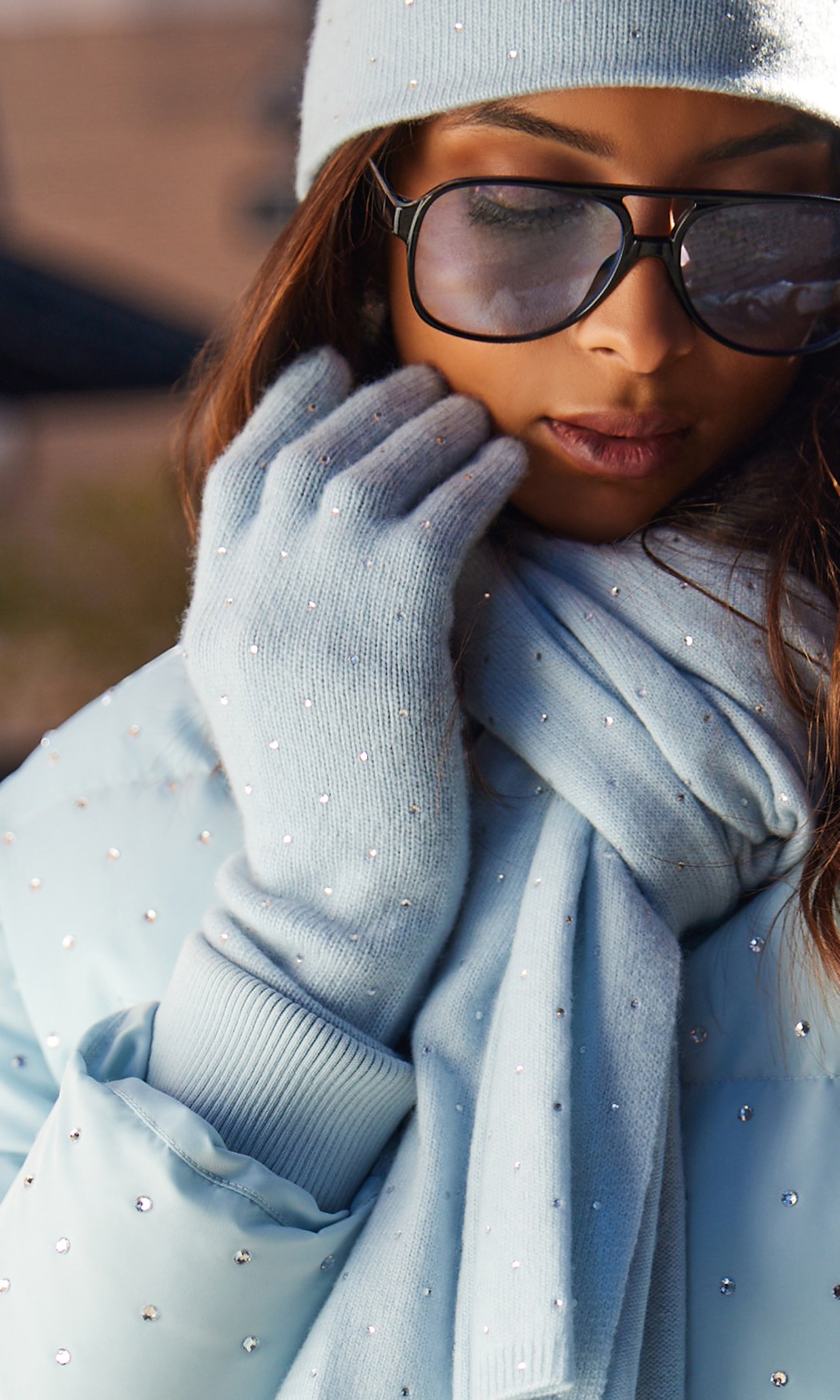 Person wearing a light blue outfit with gloves and sunglasses, standing outdoors.