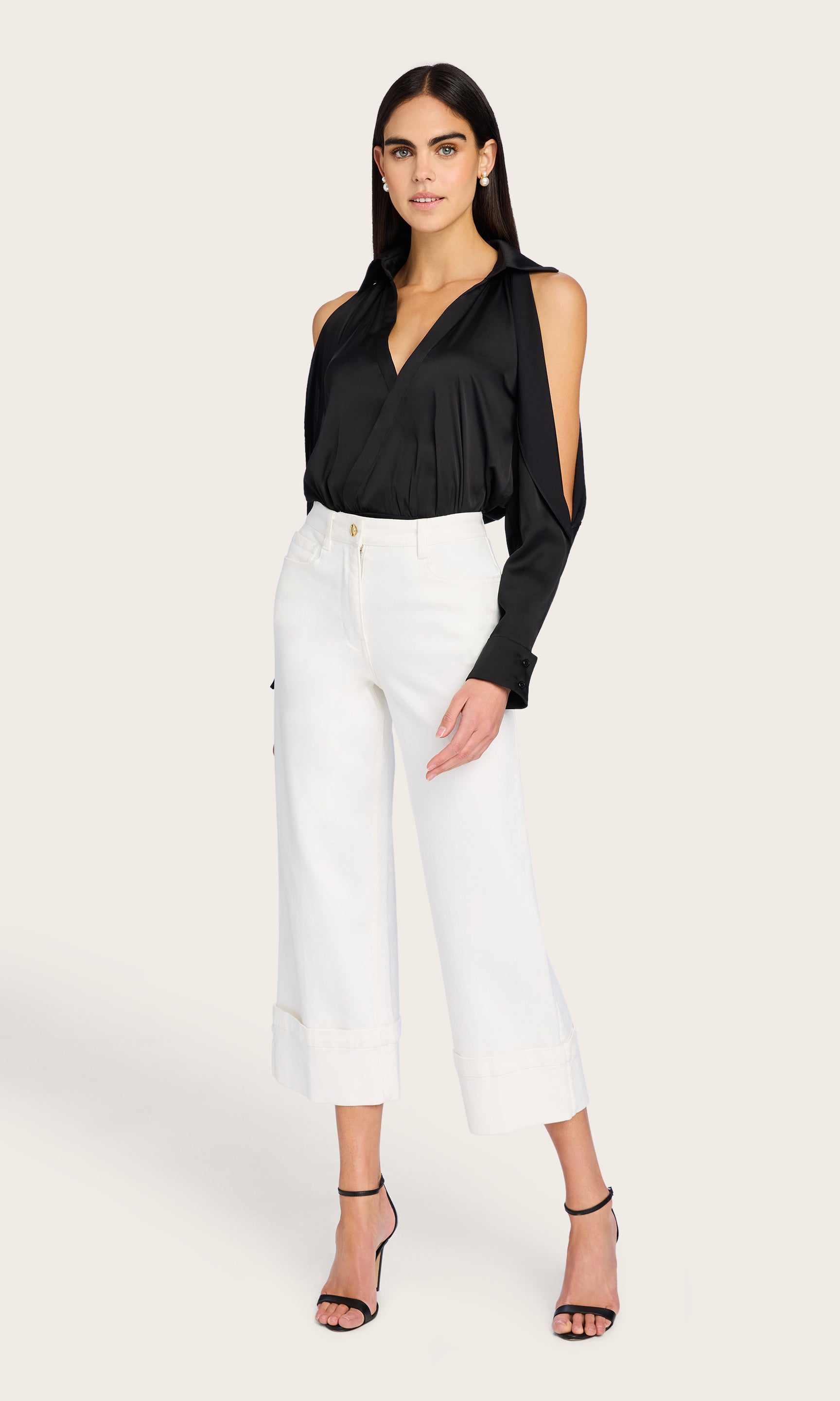 In this full body shot, the model wears the Eros Denim Pant styled with a tucked-in blouse, emphasizing the cropped length and cuffed hem.