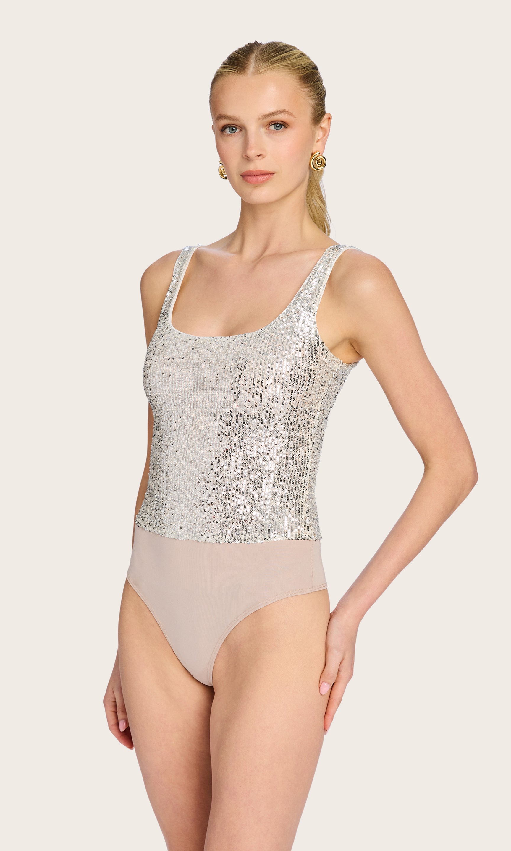 The model wears the Dina Sequin Bodysuit in a front view, styled solo to highlight its shimmering texture and sleek silhouette.