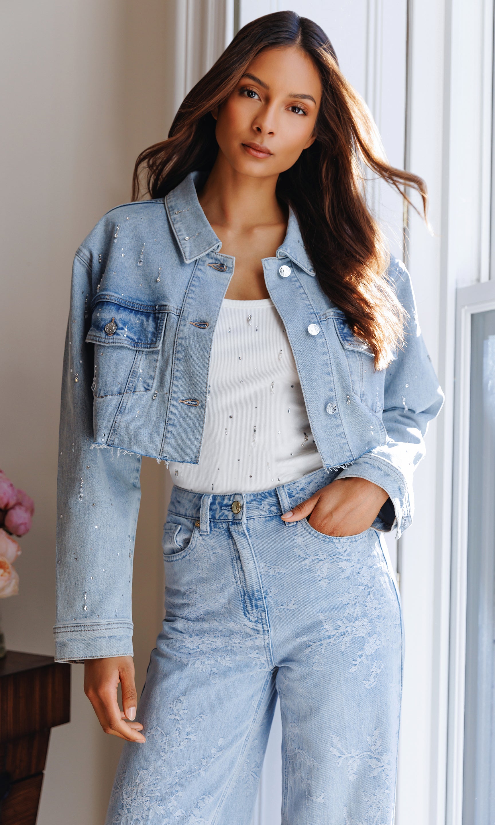 Woman wearing a light blue denim jacket and jeans indoors.