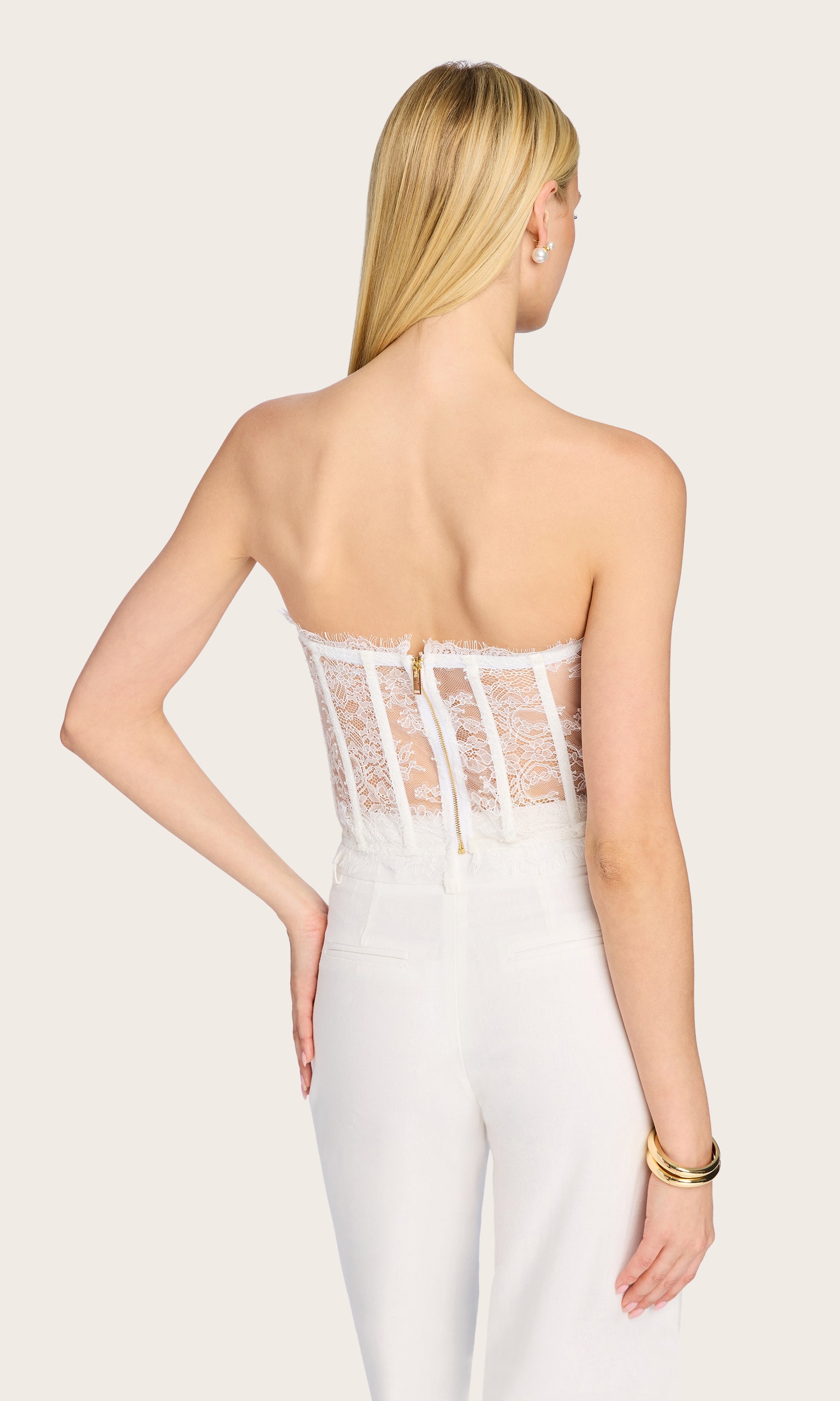 Rear view showing the clean back silhouette and strapless design of the Enya Chantilly Lace Bustier, paired with wide-leg trousers.