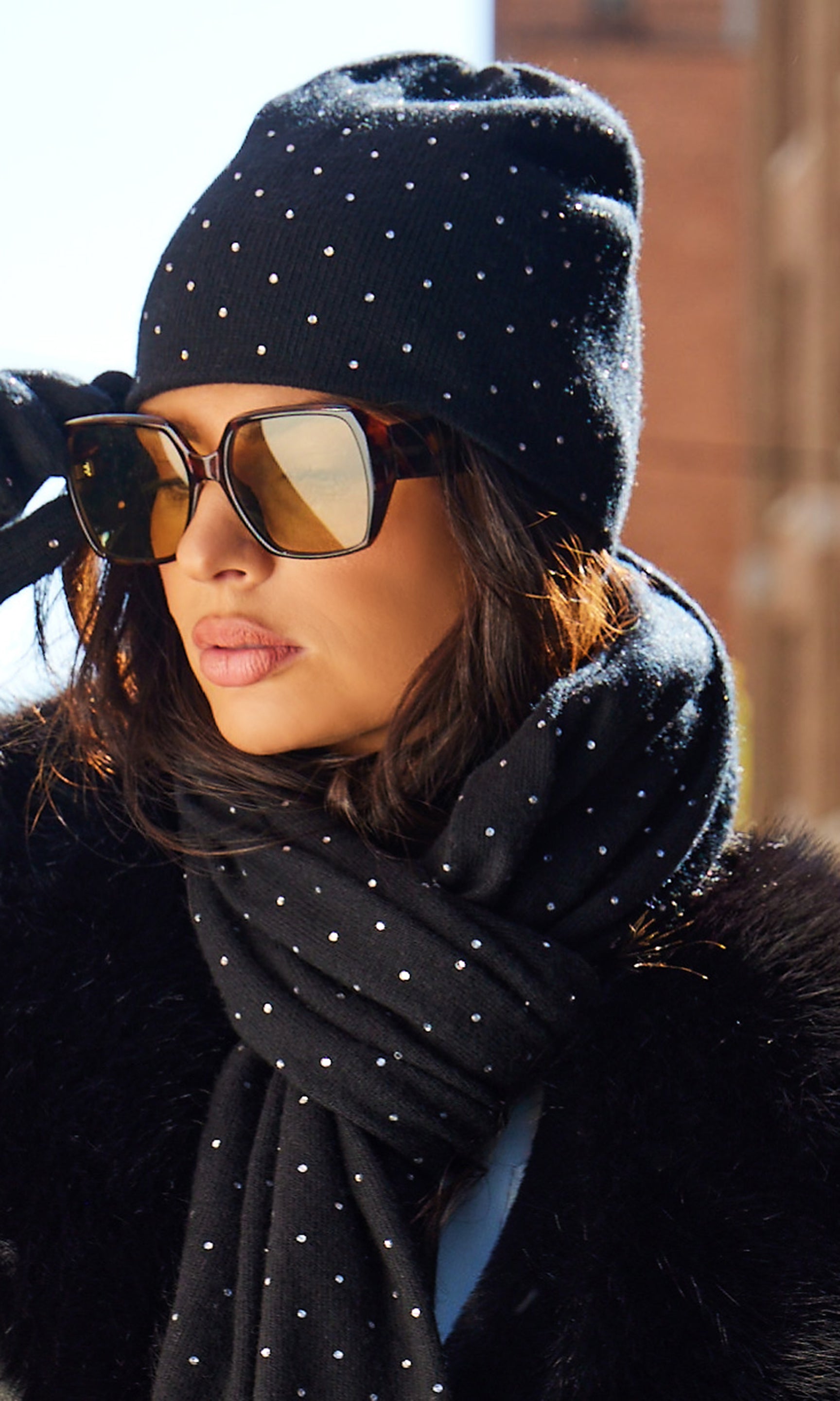 Person wearing a black beanie and scarf with reflective sunglasses.
