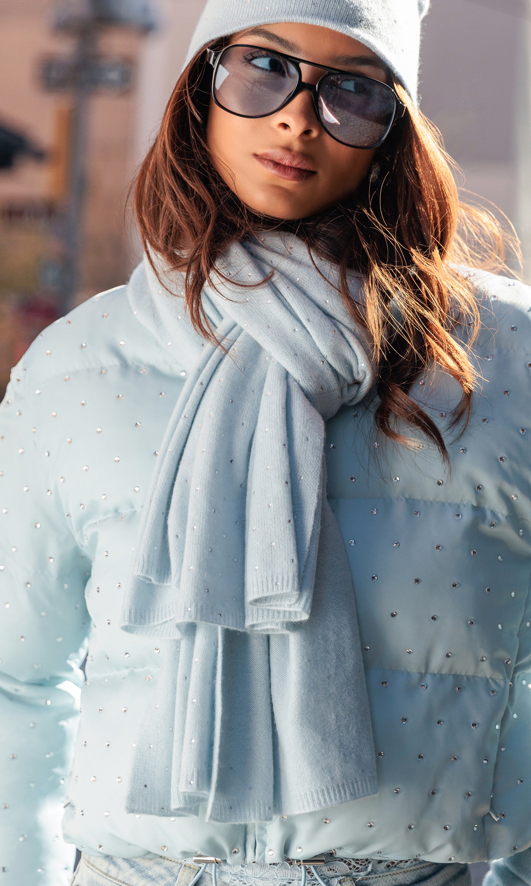 Woman wearing a light blue scarf and sunglasses with a blurred background