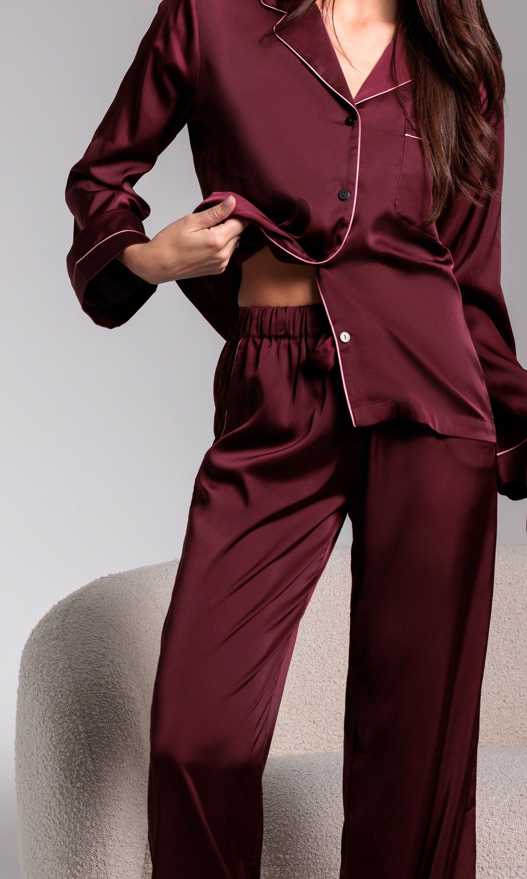 Burgundy satin pajama set worn by a person on a neutral background