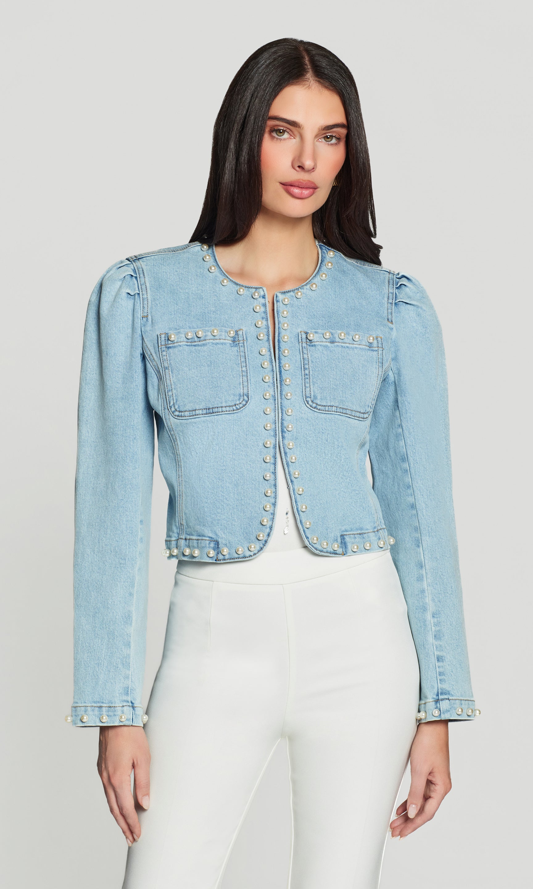 Woman wearing a light blue denim jacket on a plain background