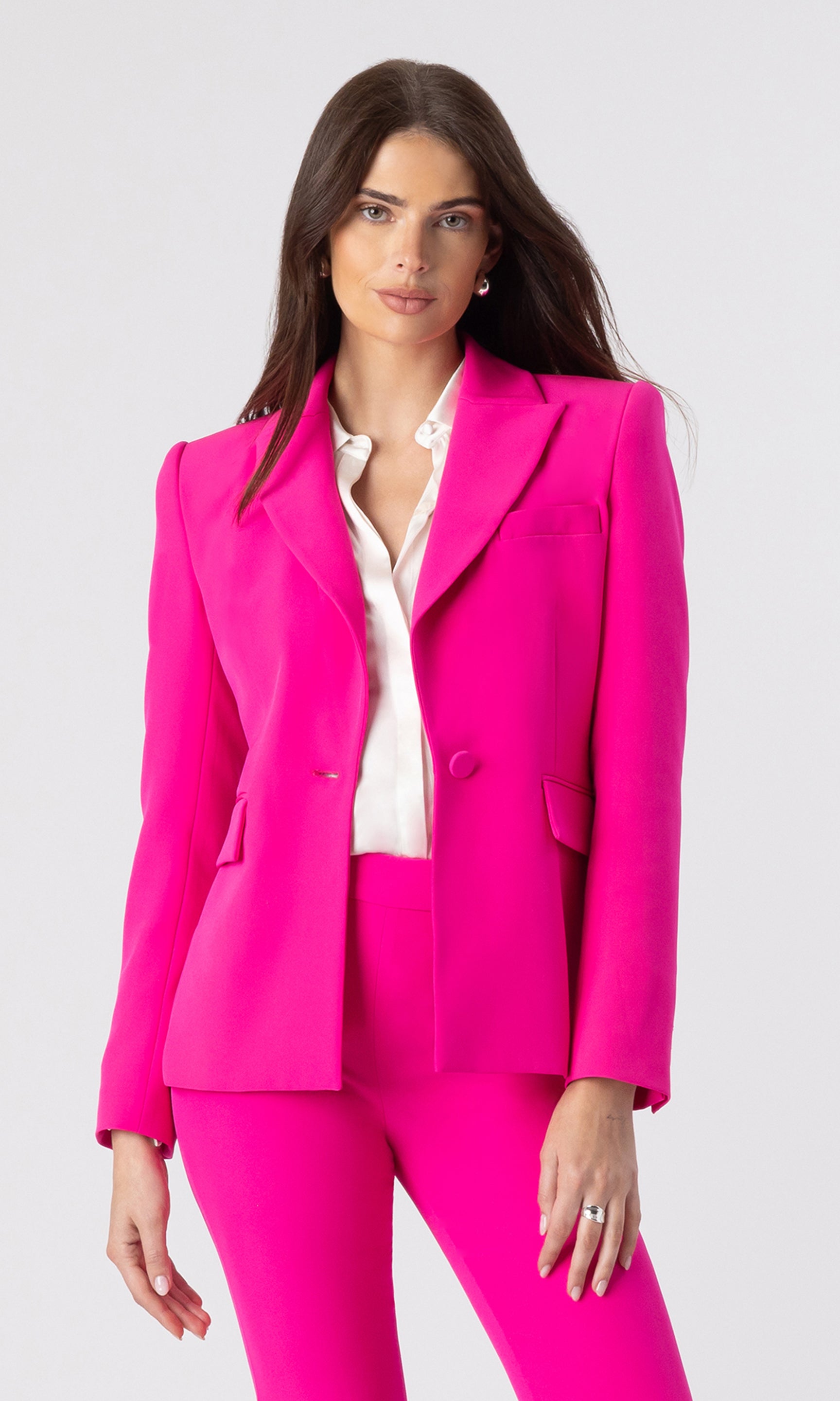 image of model wearing a hot pink blazer with matching hot pink trousers and a white button-down shirt underneath