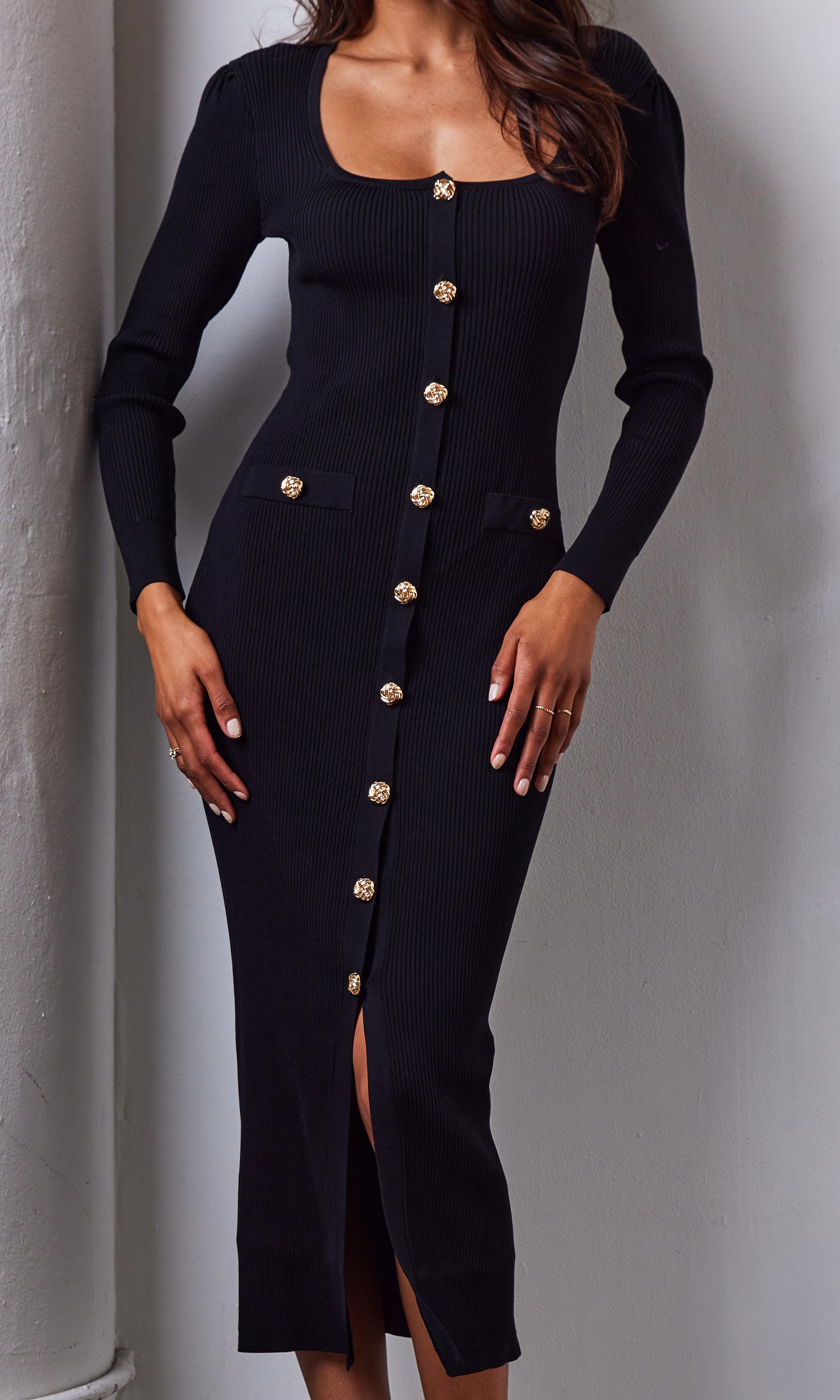Black dress with gold buttons on a plain background