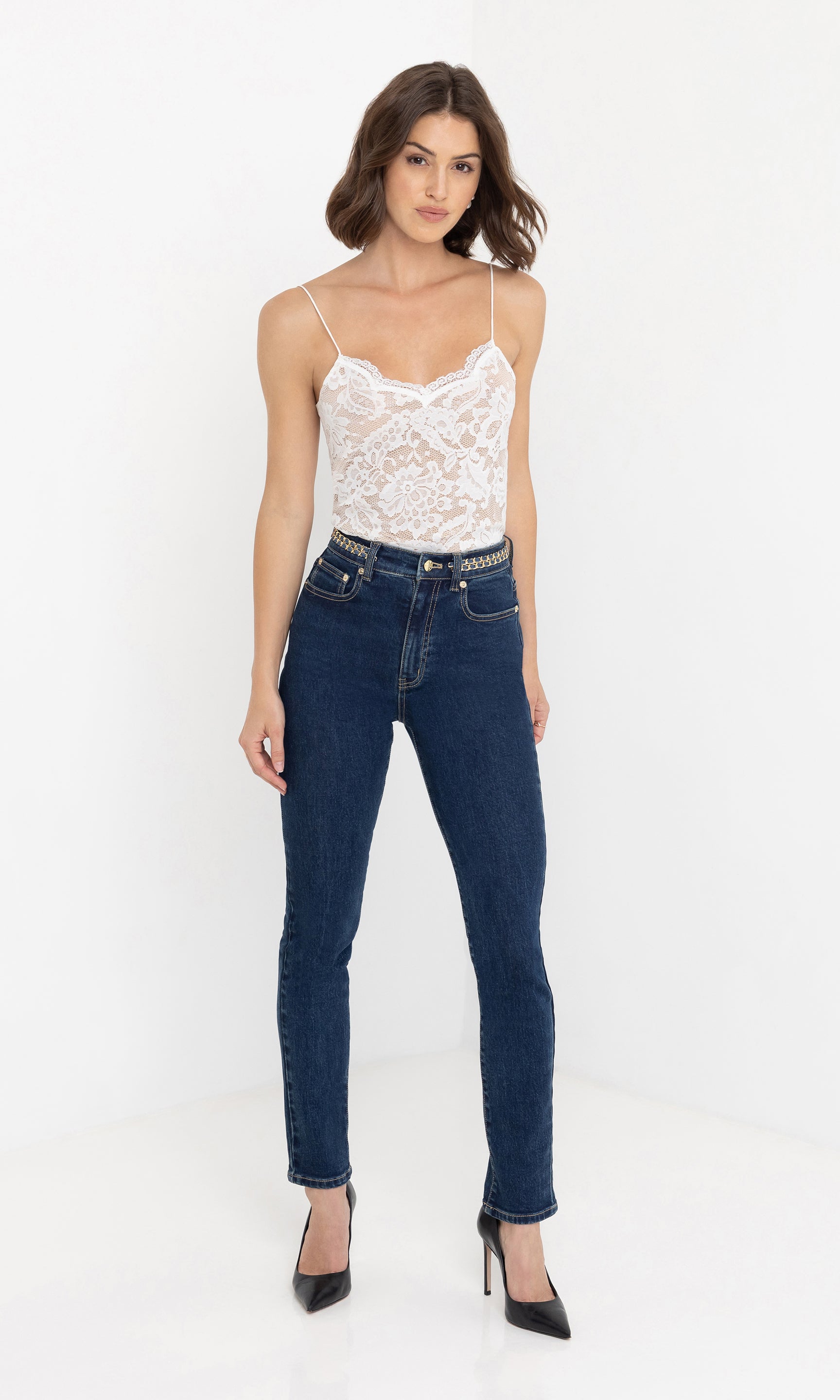 Full body front view of the Darren Denim Pants styled with a sleeveless white lace top and black heels.