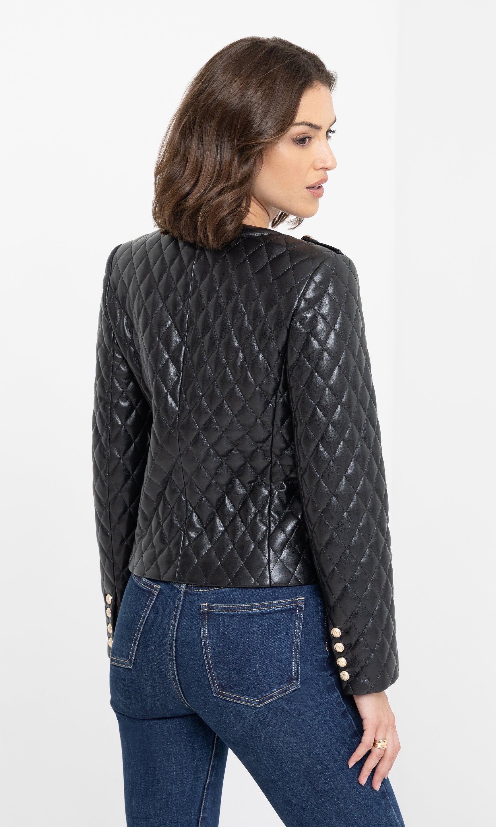 The model stands in a rear view wearing the Brevel Quilted Vegan Leather Jacket in black, showcasing the back’s quilted pattern and silhouette.
