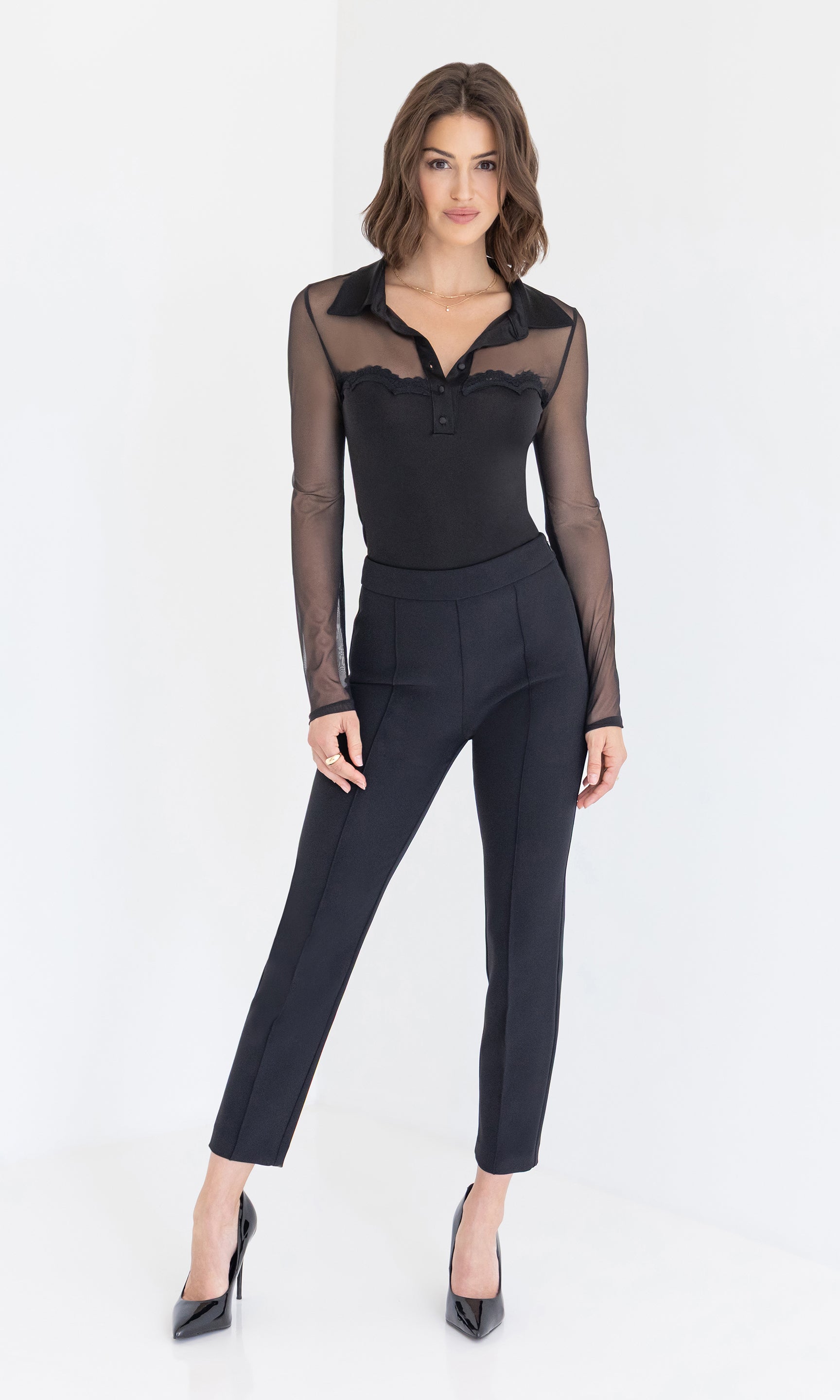 A full body front view captures the sleek look of the Brio Mesh Combo Top styled with black high-waisted pants and classic heels for a polished finish.
