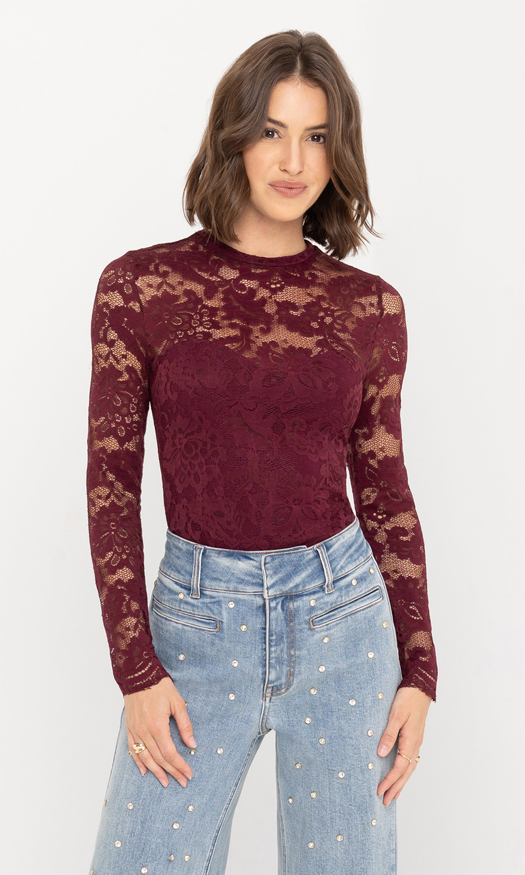 Front view of the model wearing the Clayton Lace Top in deep burgundy, styled with light blue high-waisted jeans.