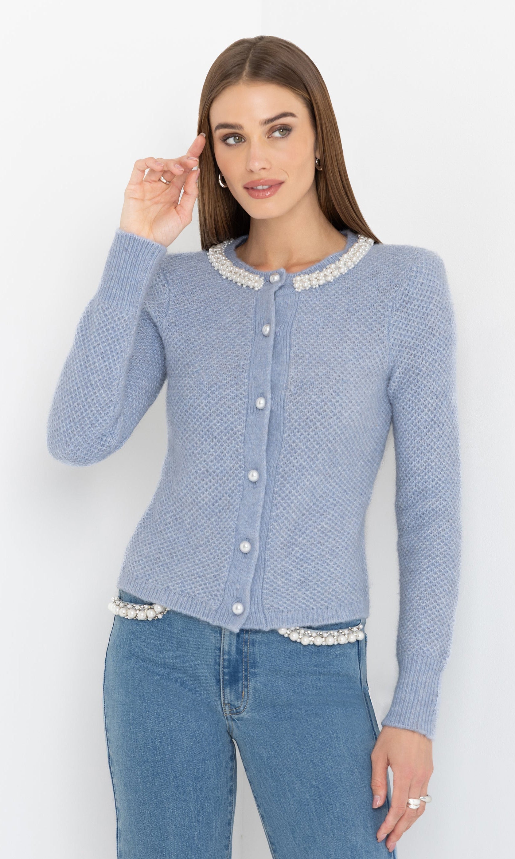Angled front view of the Clove Cardigan in soft blue, showing the pearl button details and feminine silhouette.