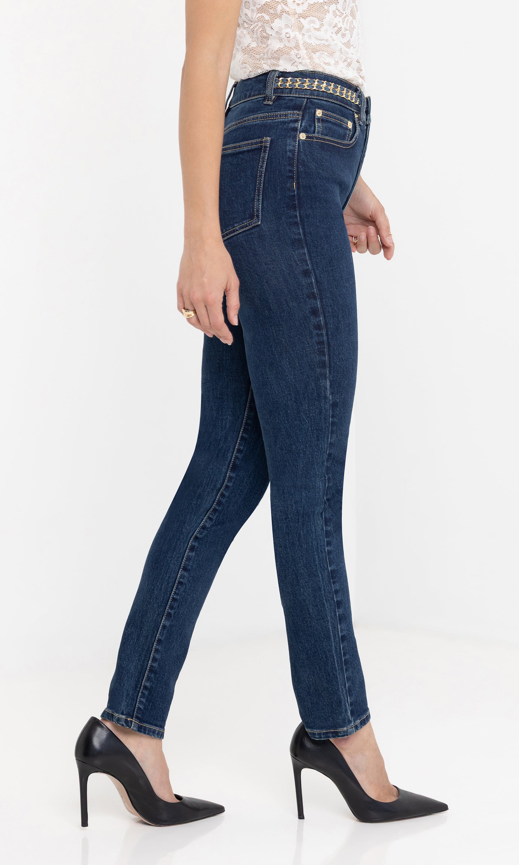 Side view of the Darren Denim Pants in dark blue, styled with black heels and a white lace top, highlighting the slim fit and mid-rise waistband.