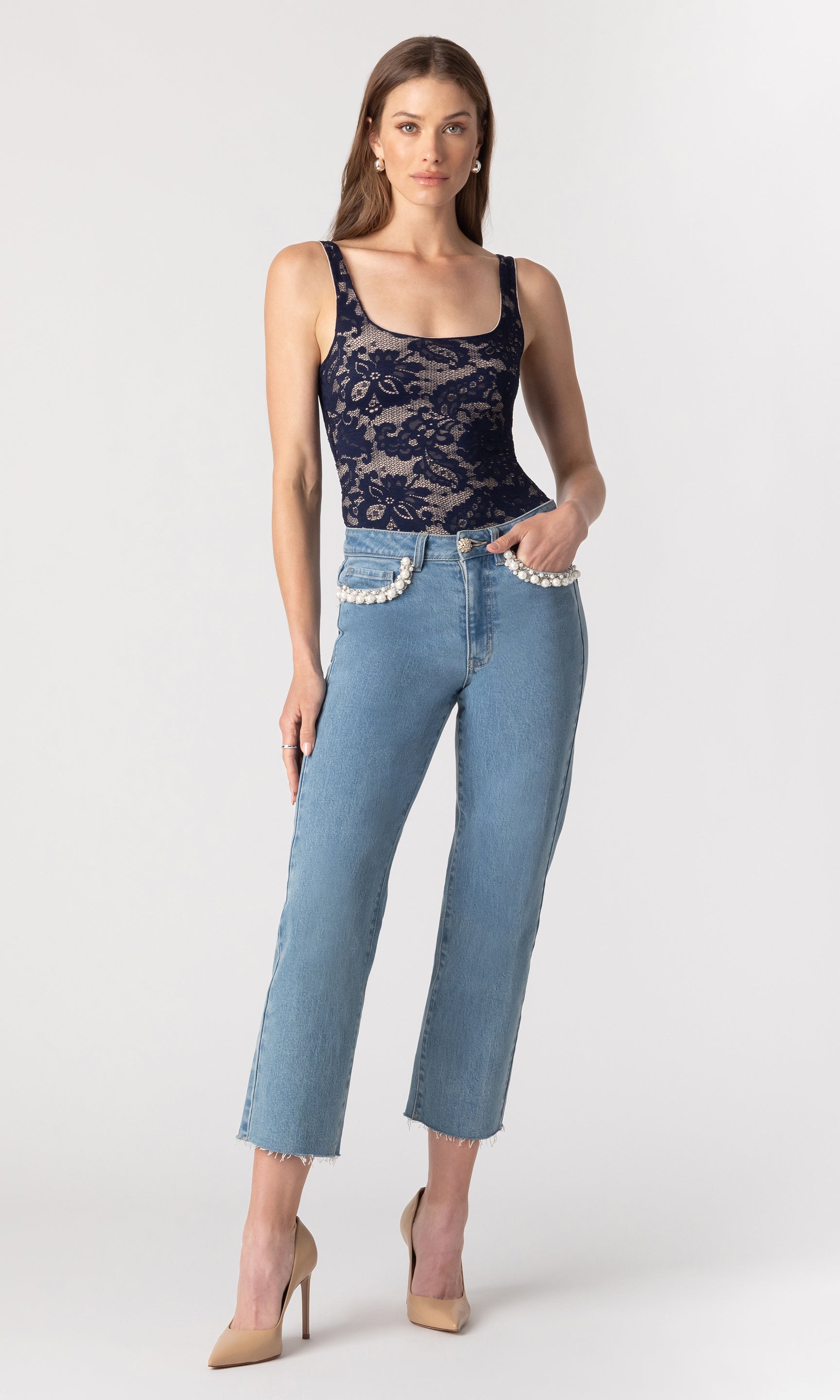 fully body image of model posing with her hand in her pant pocket, wearing the Baylor jeans paired with a navy lace top and beige heels