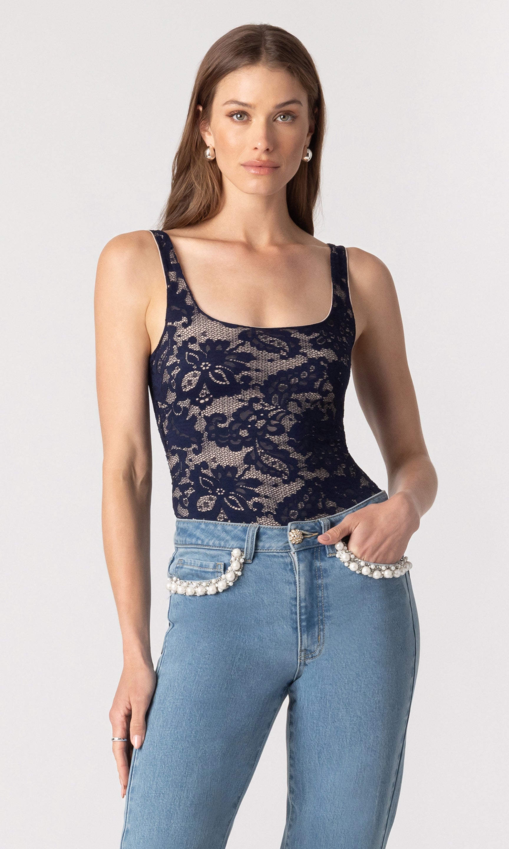 image of model wearing the Gina lace bodysuit in a navy and beige color paired with blue jeans