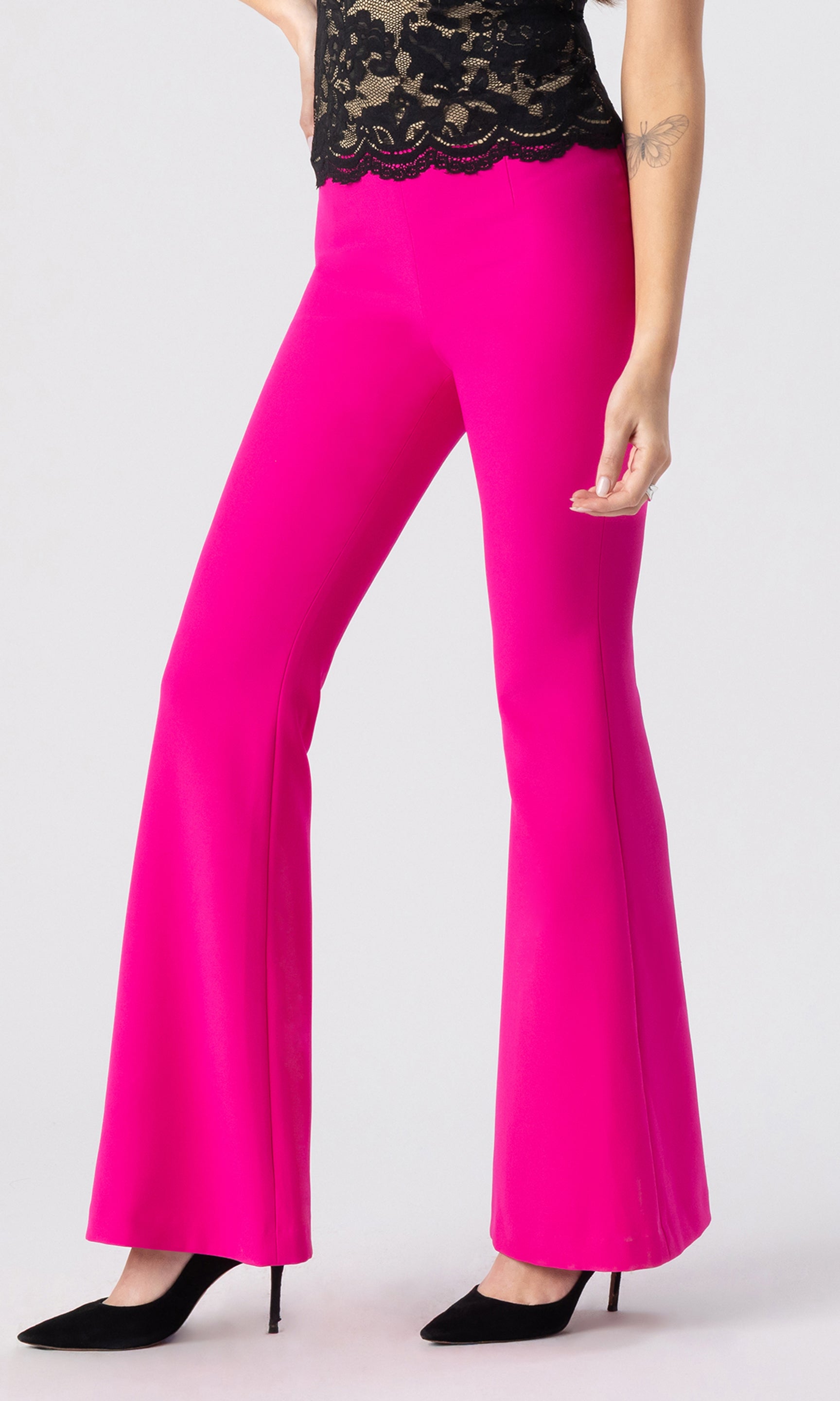 cropped side view image of model wearing the Wesley crepe pants in hot pink, paired with a black/beige lace top and black heels