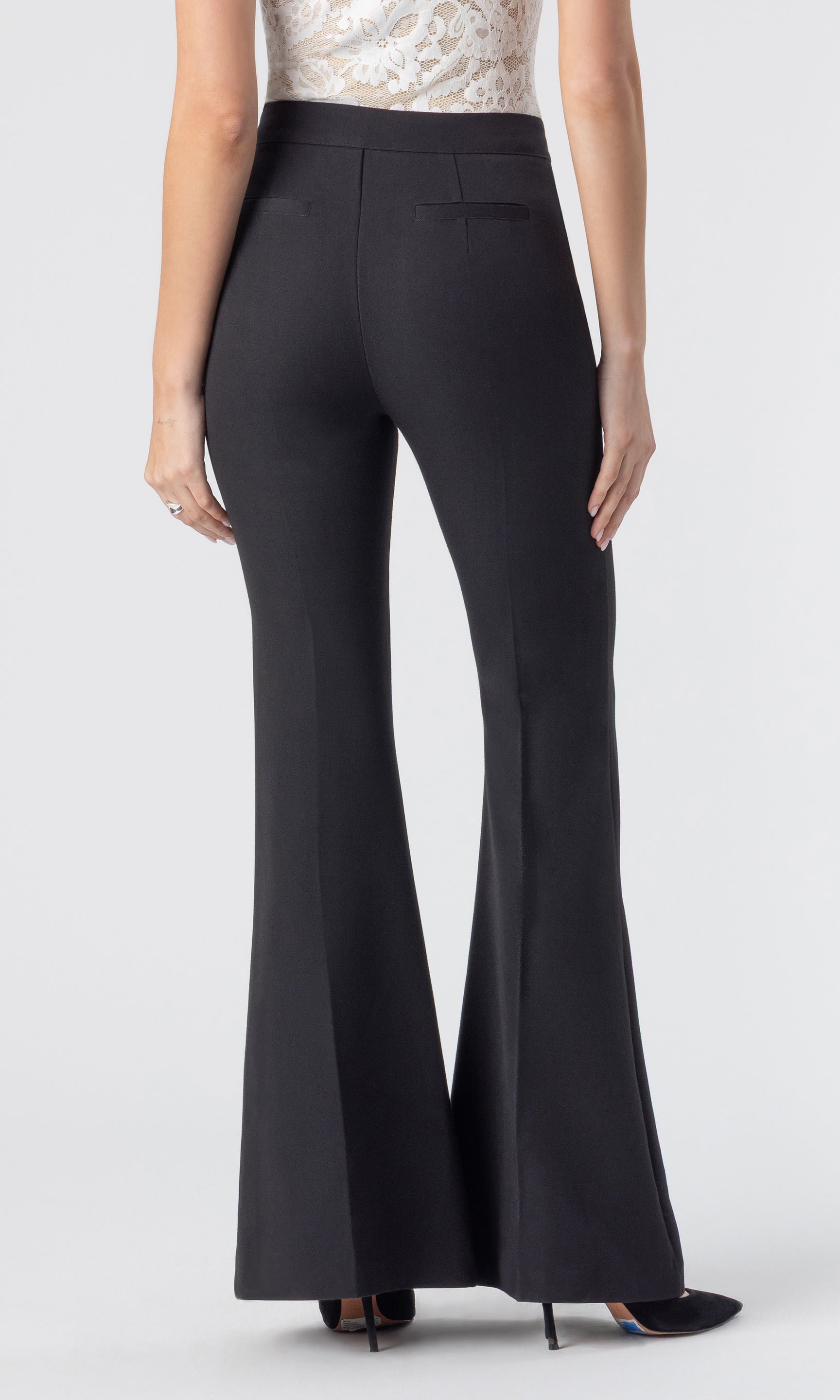 cropped back view image of model wearing the Wesley crepe pants in black, paired with a white/beige lace tank and black heels