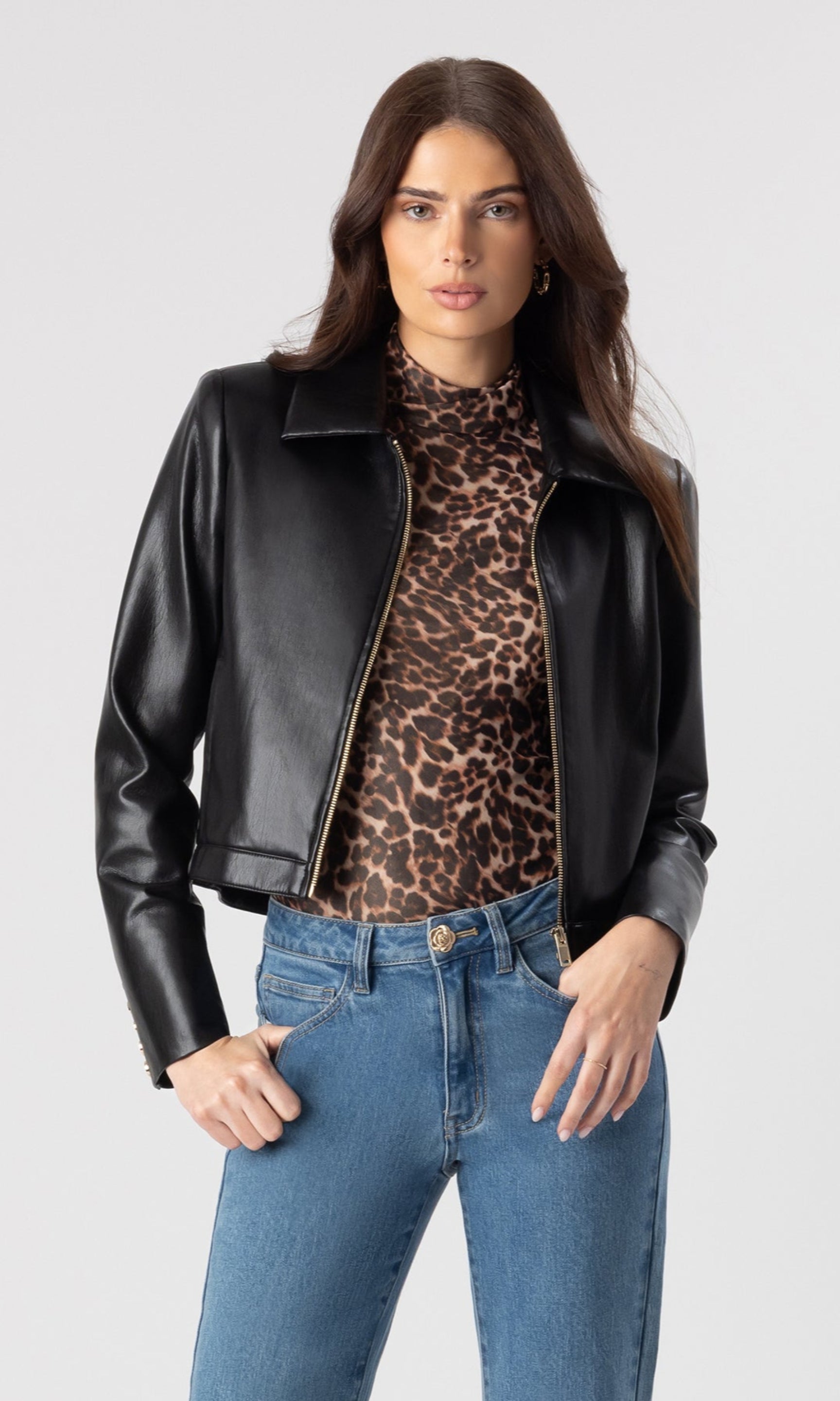 image of model wearing the Lola vegan leather jacket in black over a leopard print blouse and paired with blue denim jeans
