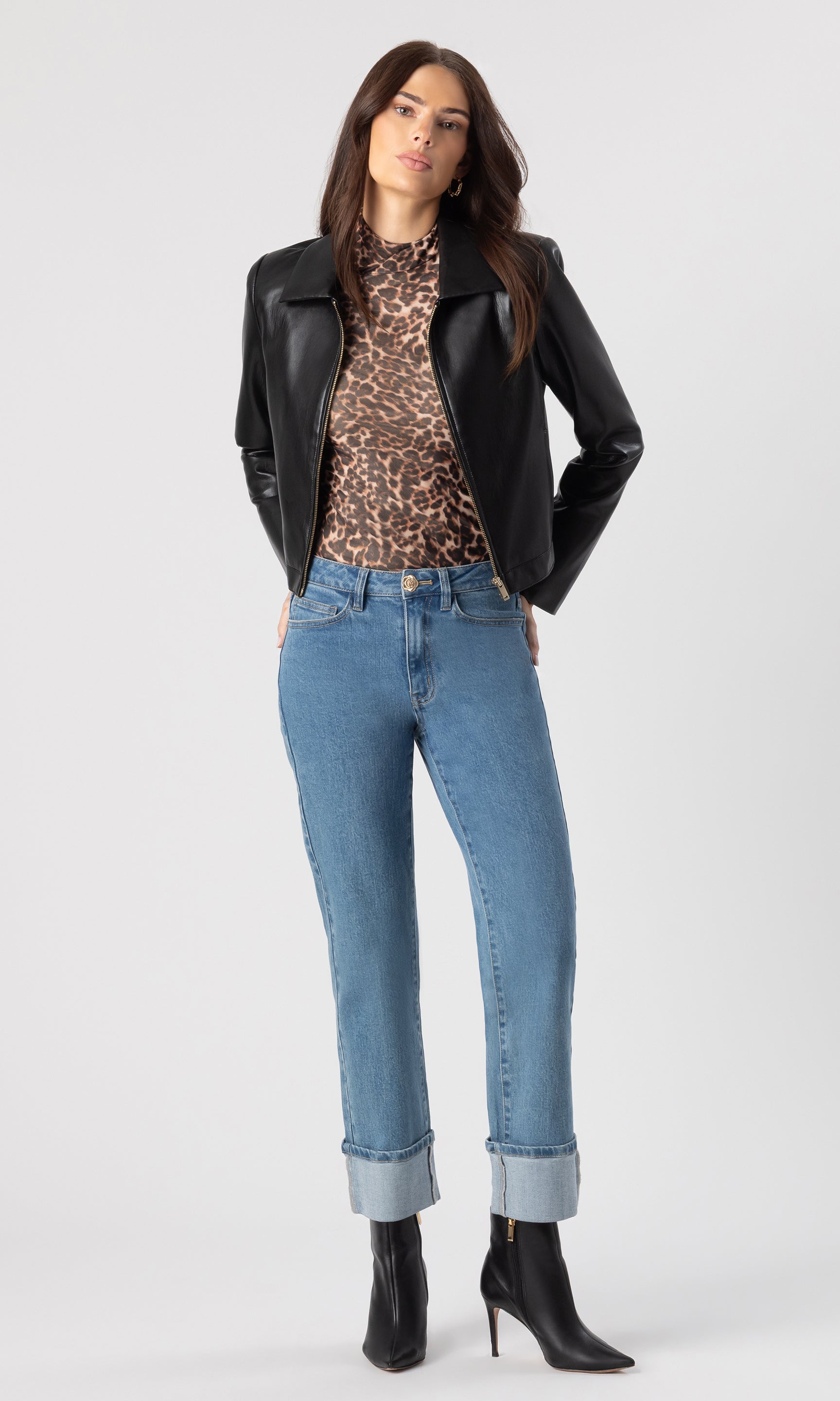 full body image of model wearing the Milo mesh bodysuit in a leopard print with a black began-leather jacket over it and the Ryland dark blue jeans with black heeled booties