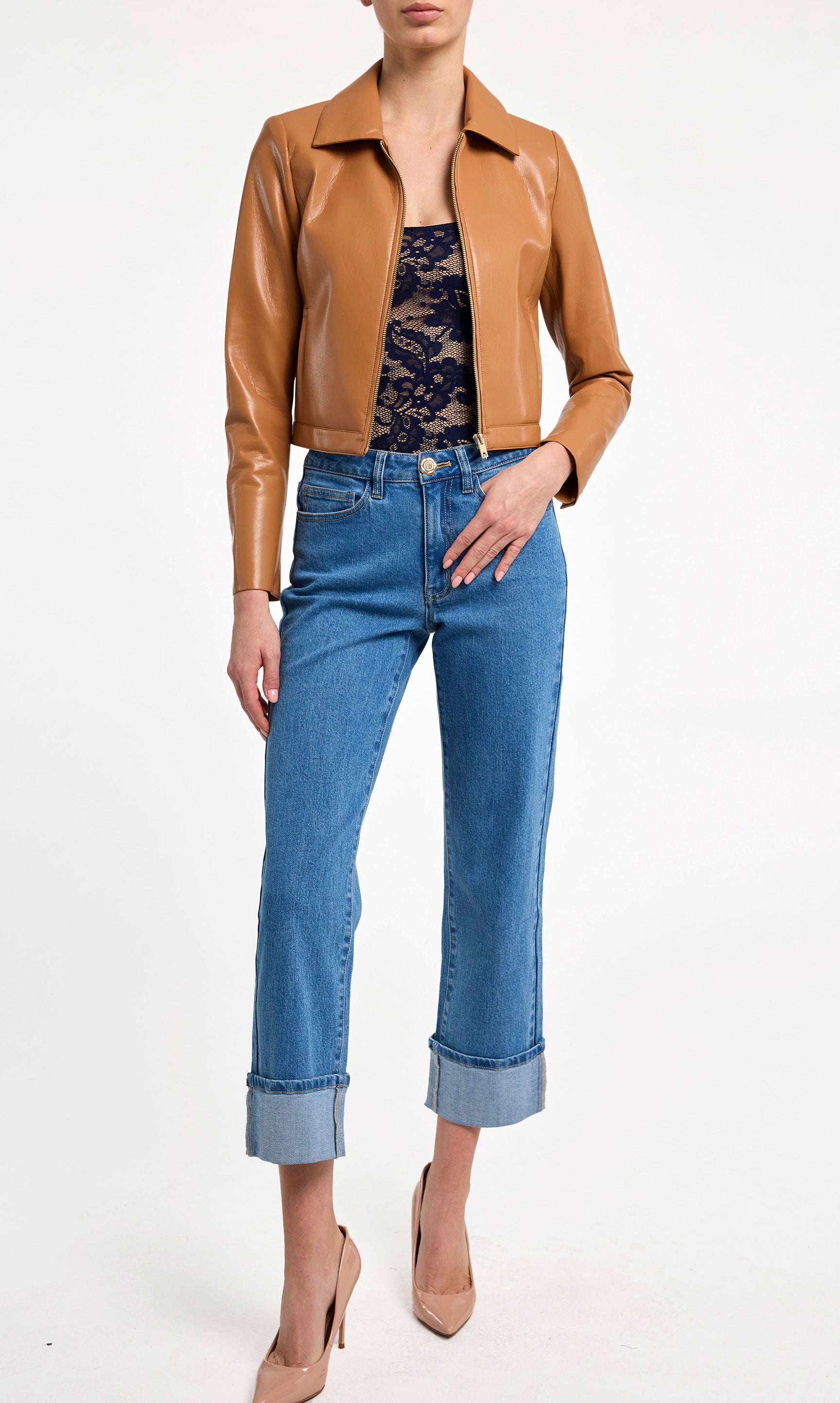 Person wearing a brown leather jacket, blue jeans, and beige heels on a white background
