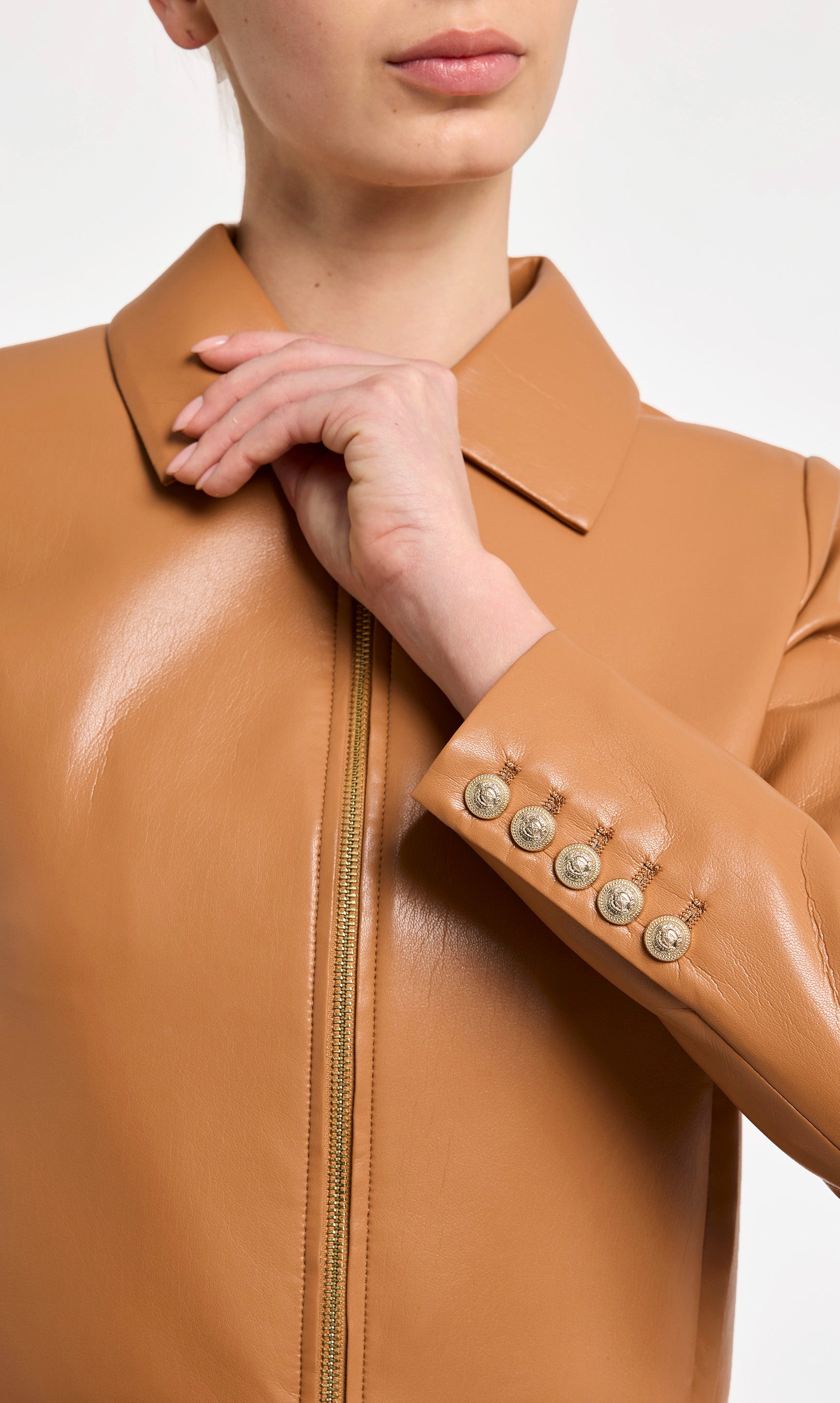 Close-up of a person wearing a brown leather jacket with a zipper and button details.
