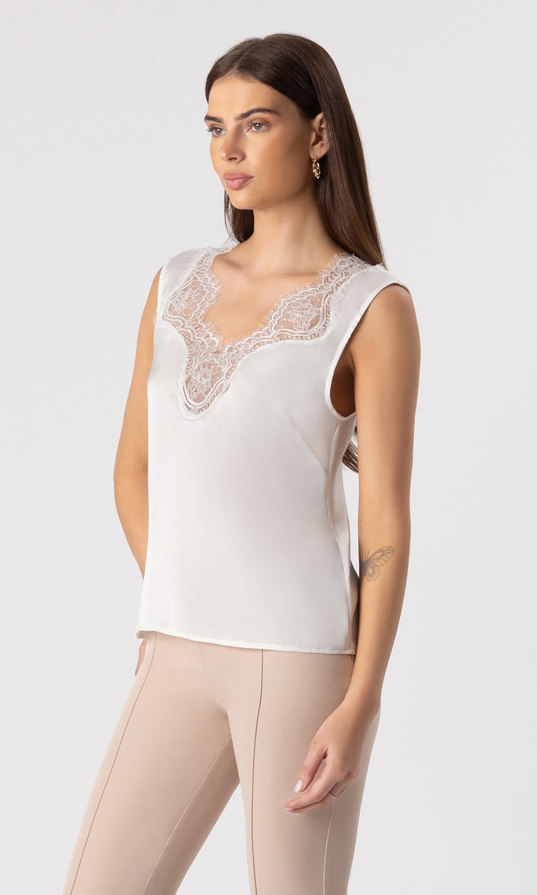 3/4 side view image of model wearing the Gladis tank in white, paired with beige trousers
