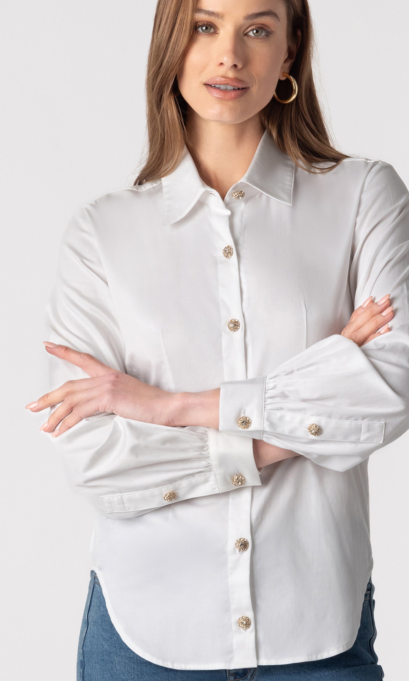 zoomed in image of model wearing the Lonny button-down blouse paired with dark blue jeans, showcasing the gold buttons down the front and on the sleeves
