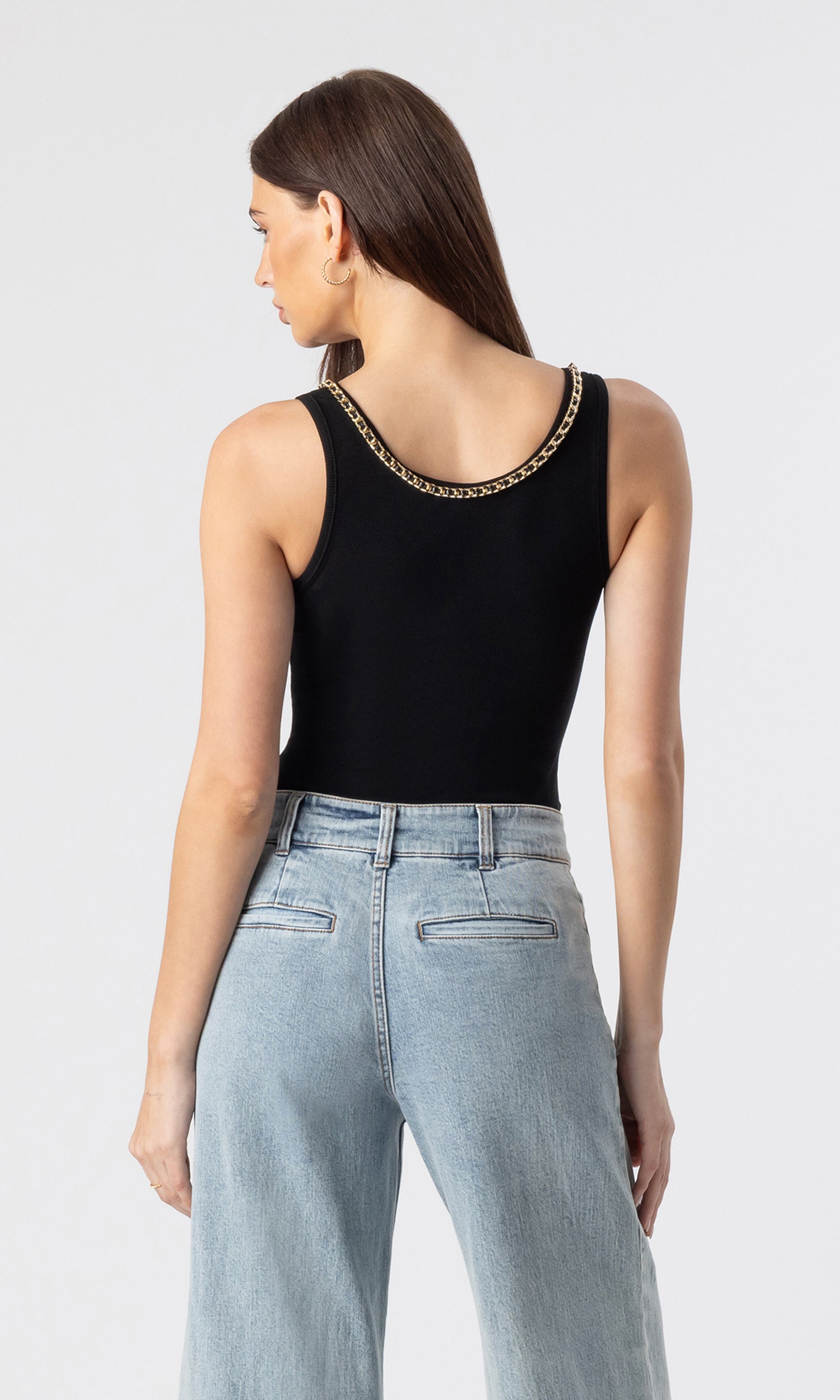 back view image of model wearing the Mabel tank in black with a chain embellished neckline paired with light blue jeans