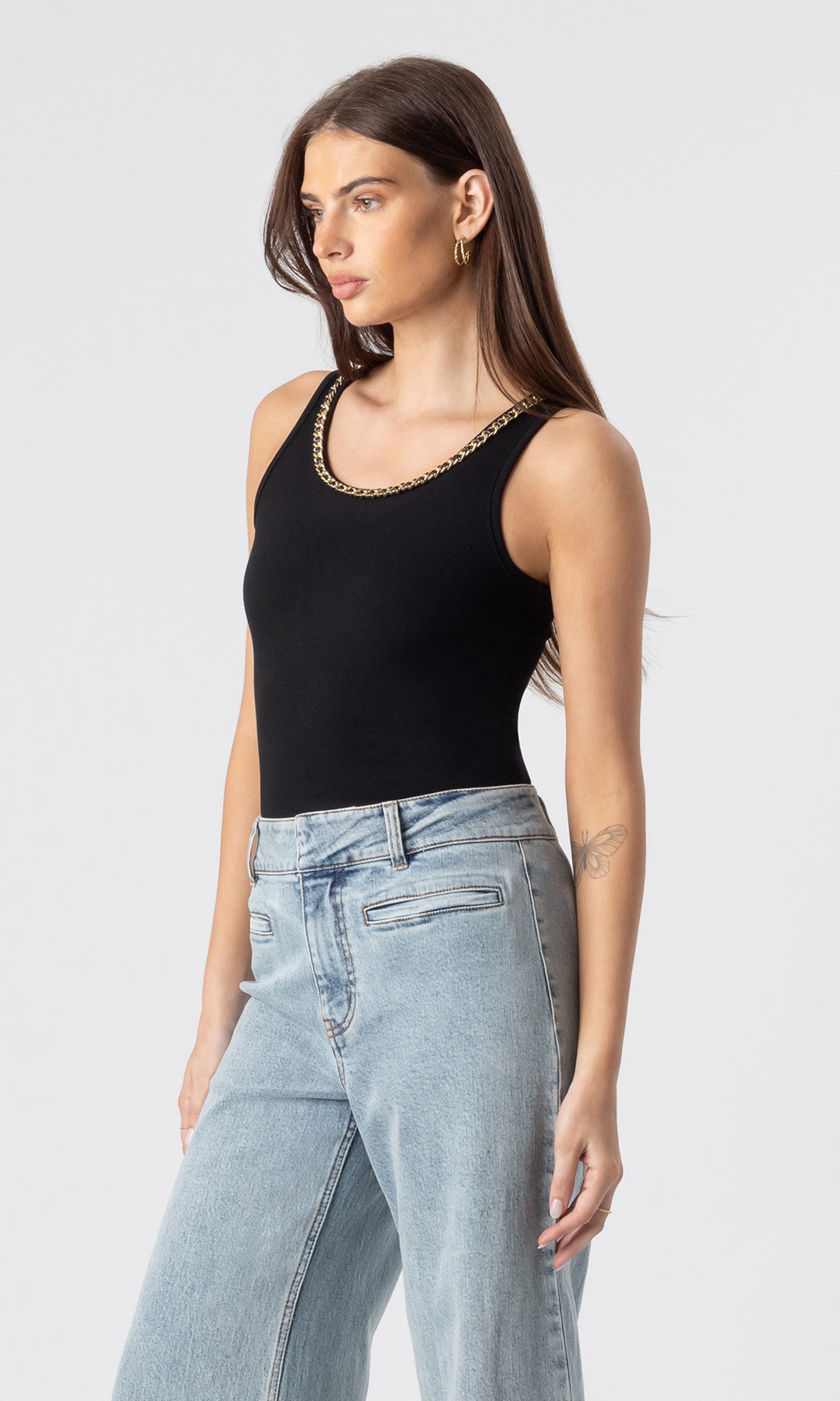 side view image of model wearing the Mabel tank in black with a chain embellished neckline paired with light blue jeans