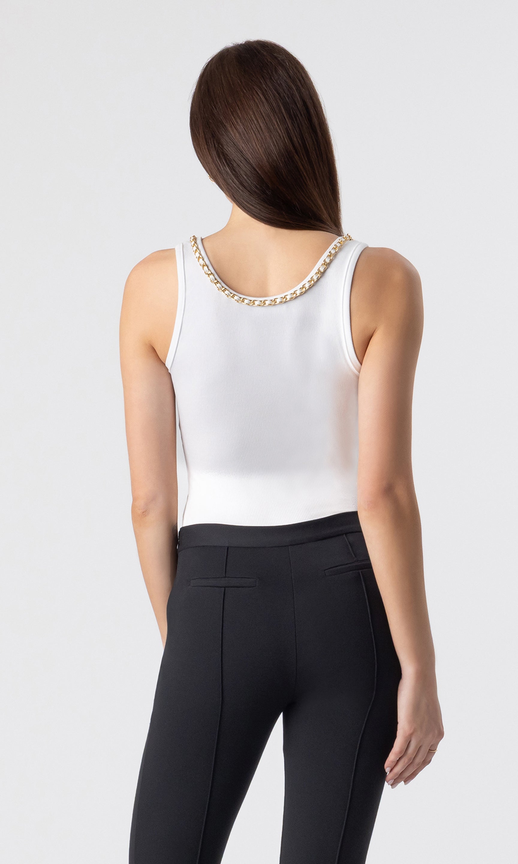 back view image of model wearing the Mabel tank in white with a chain embellished neckline paired with black leggings