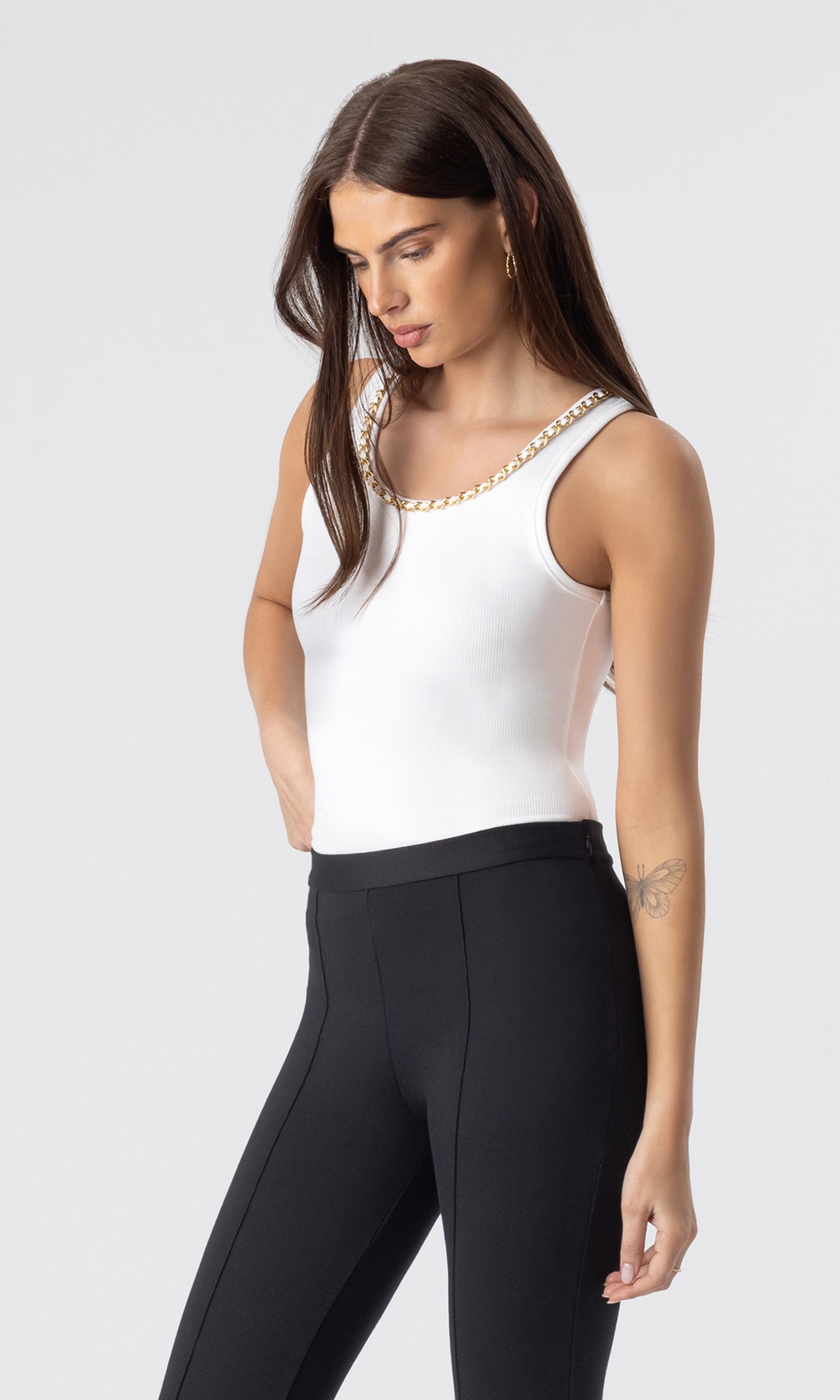 3/4 view image of model wearing the Mabel tank in white with a chain embellished neckline paired with black leggings