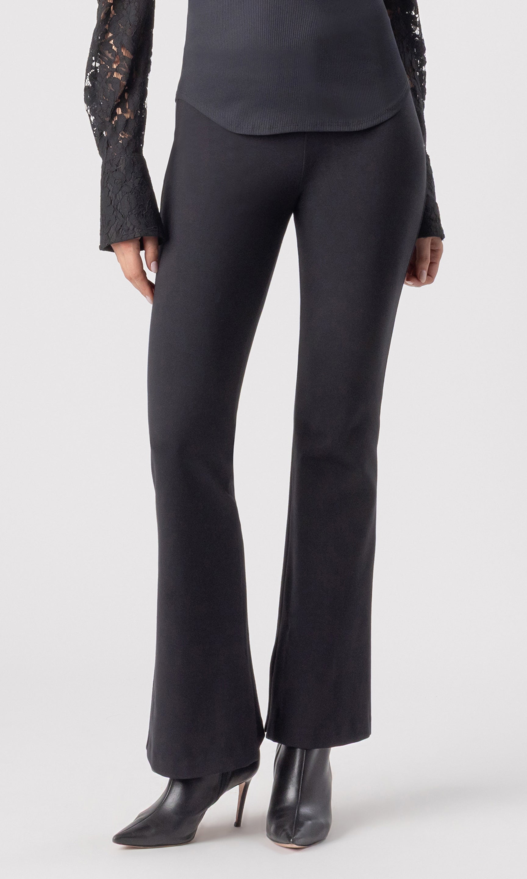 cropped front view image of model wearing the Murray Ponte Leggings in black, paired with a black blouse and black heeled booties
