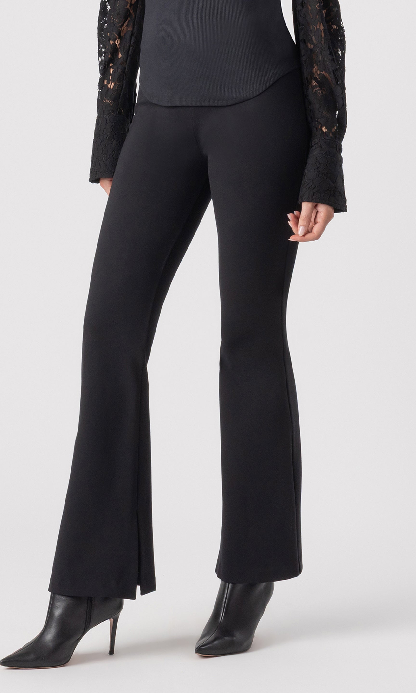 cropped 3/4 side view image of model wearing the Murray Ponte Leggings in black, paired with a black blouse and black heeled booties