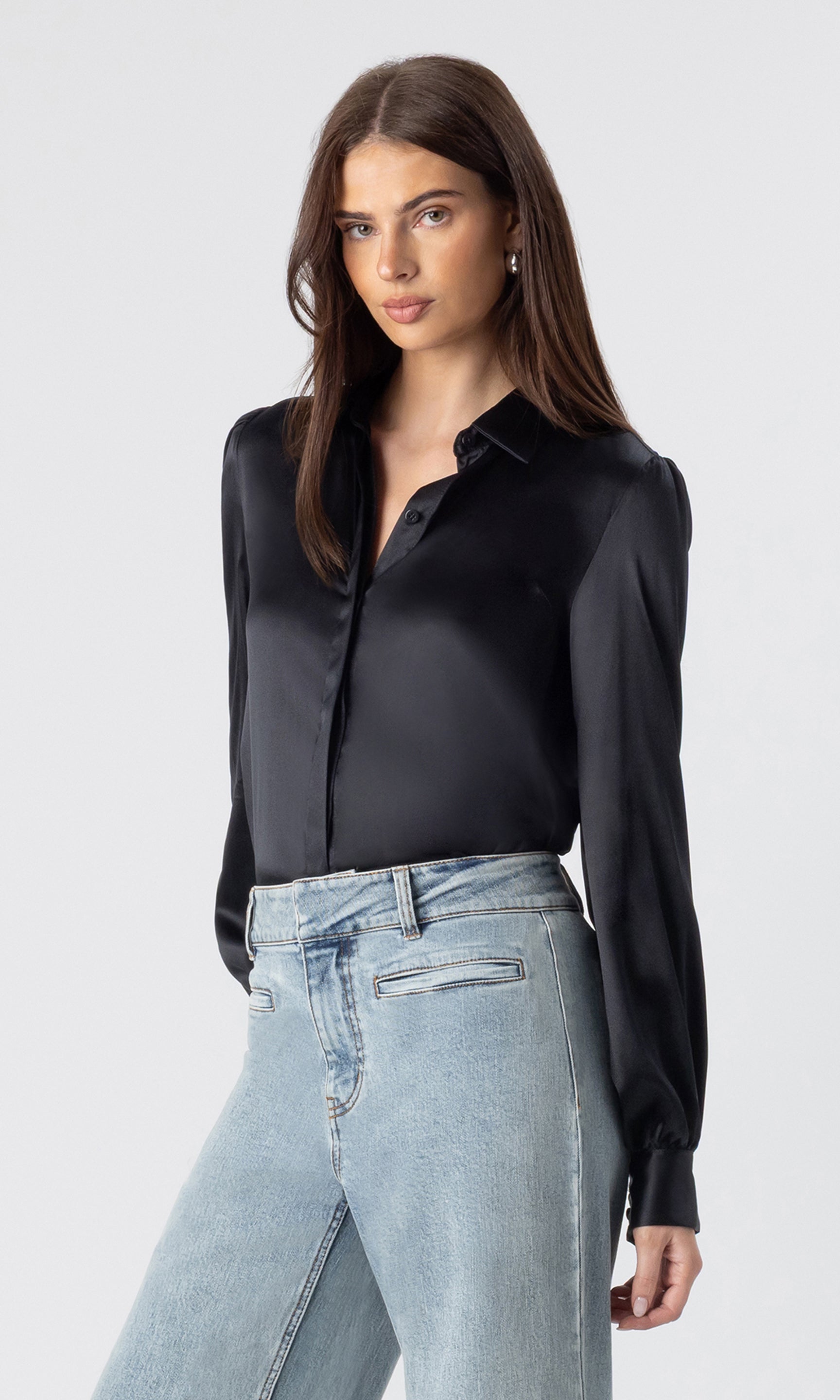 side view image of model wearing the Maxwell blouse in black tucked into light blue jeans
