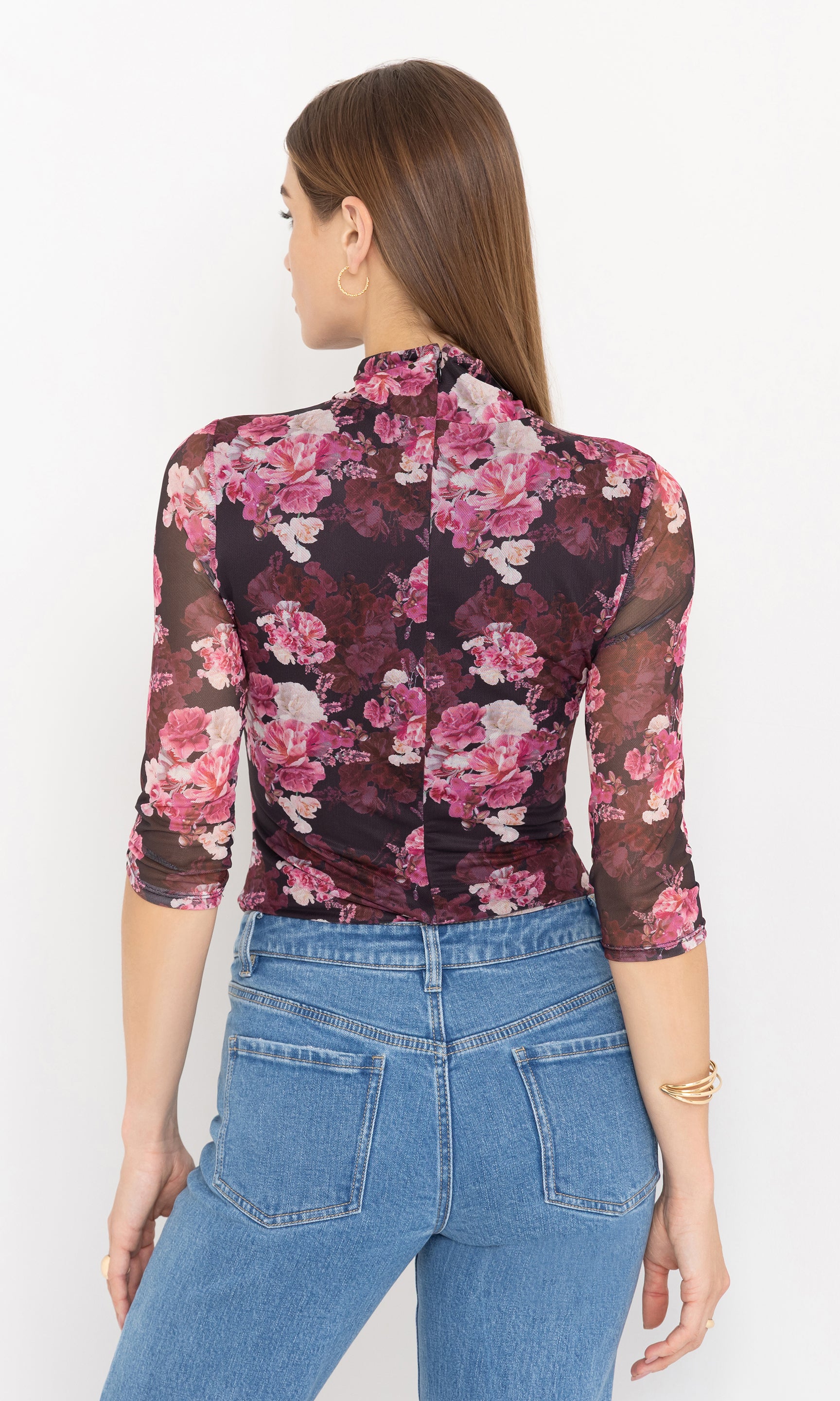 Back view of woman wearing a floral blouse and jeans on a white background