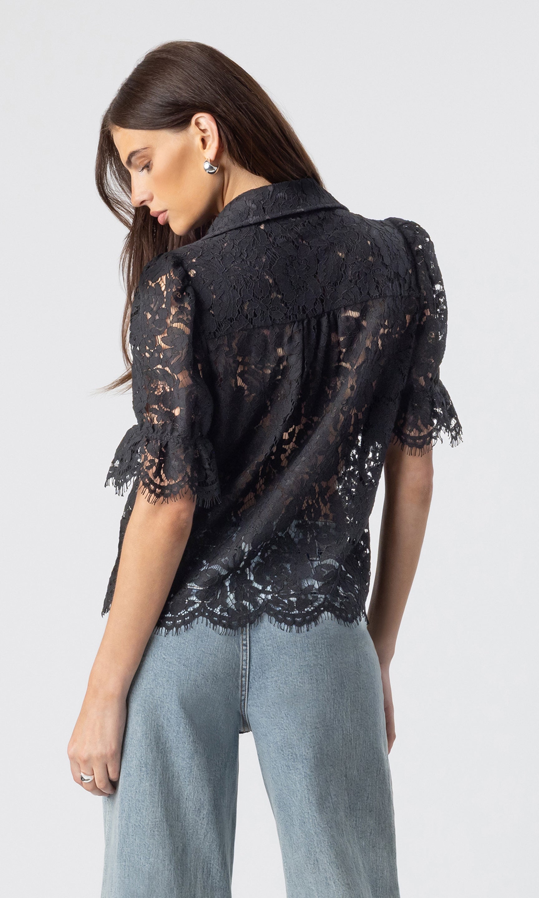 back view image of model wearing the Mina lace shirt in black paired with light blue jeans